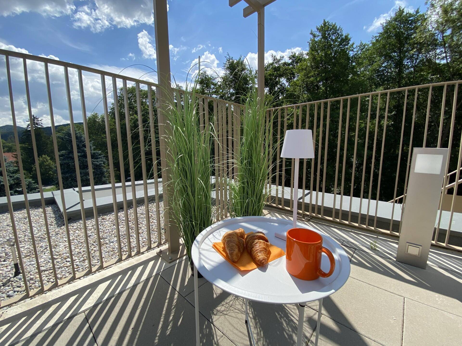 Gemütliche Sitzecke auf der Terrasse mit Frühstück und dekorativen Pflanzen.