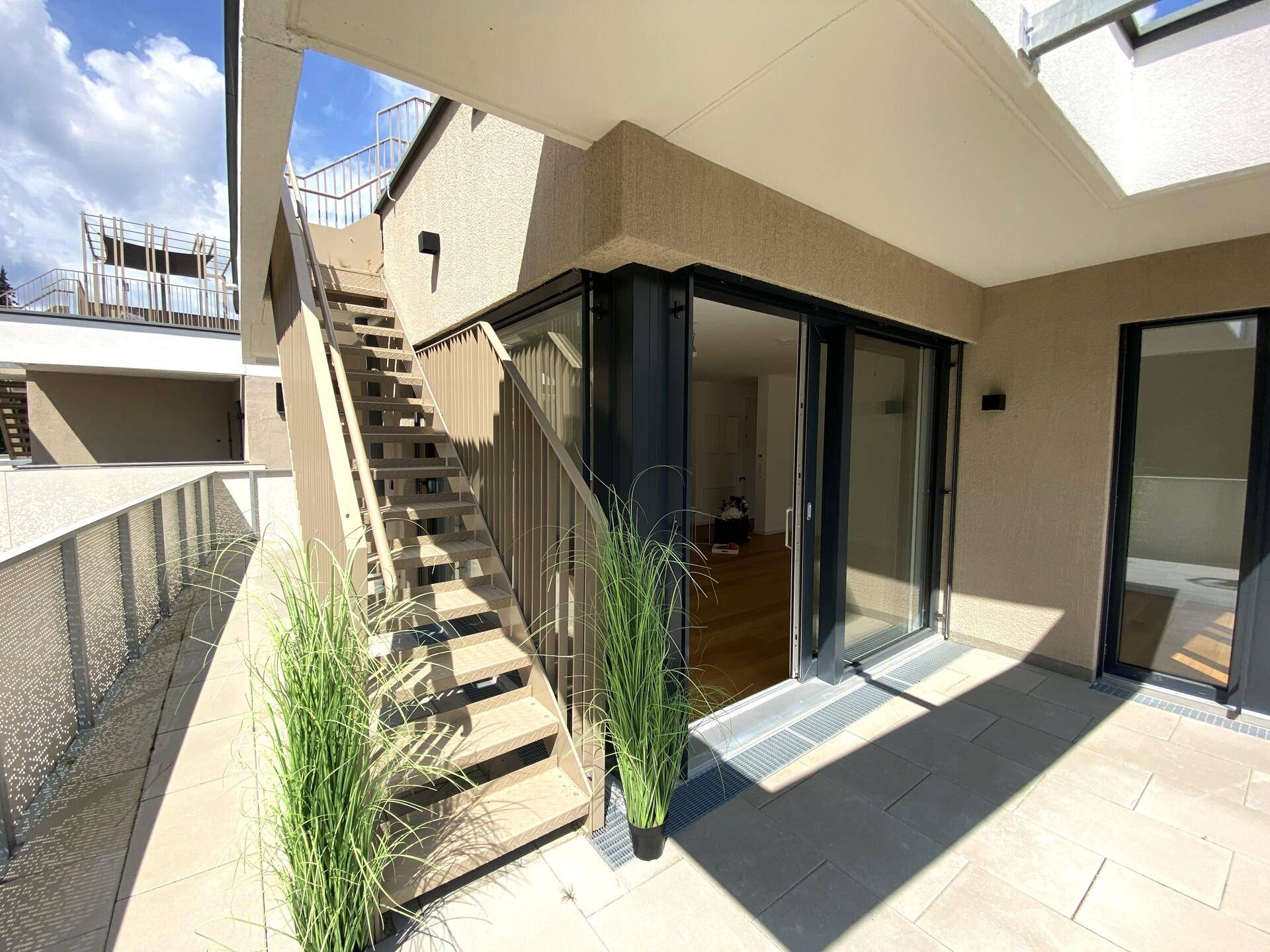 Geräumige Terrasse mit Zugang zum Innenbereich und Treppe zu weiteren Ebenen.
