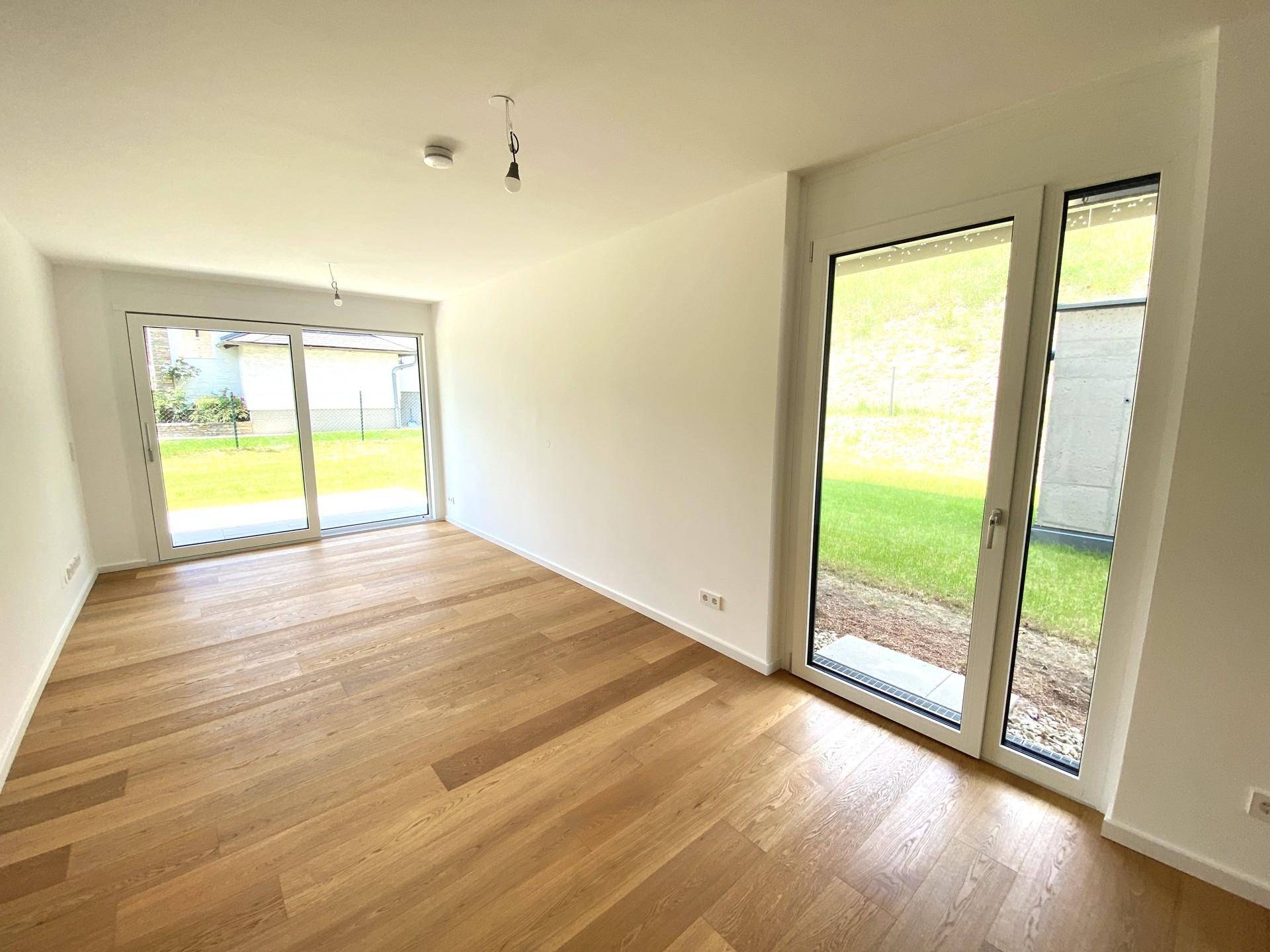 Heller Wohnraum mit hochwertigem Parkettboden und großen Fenstern zum Garten.