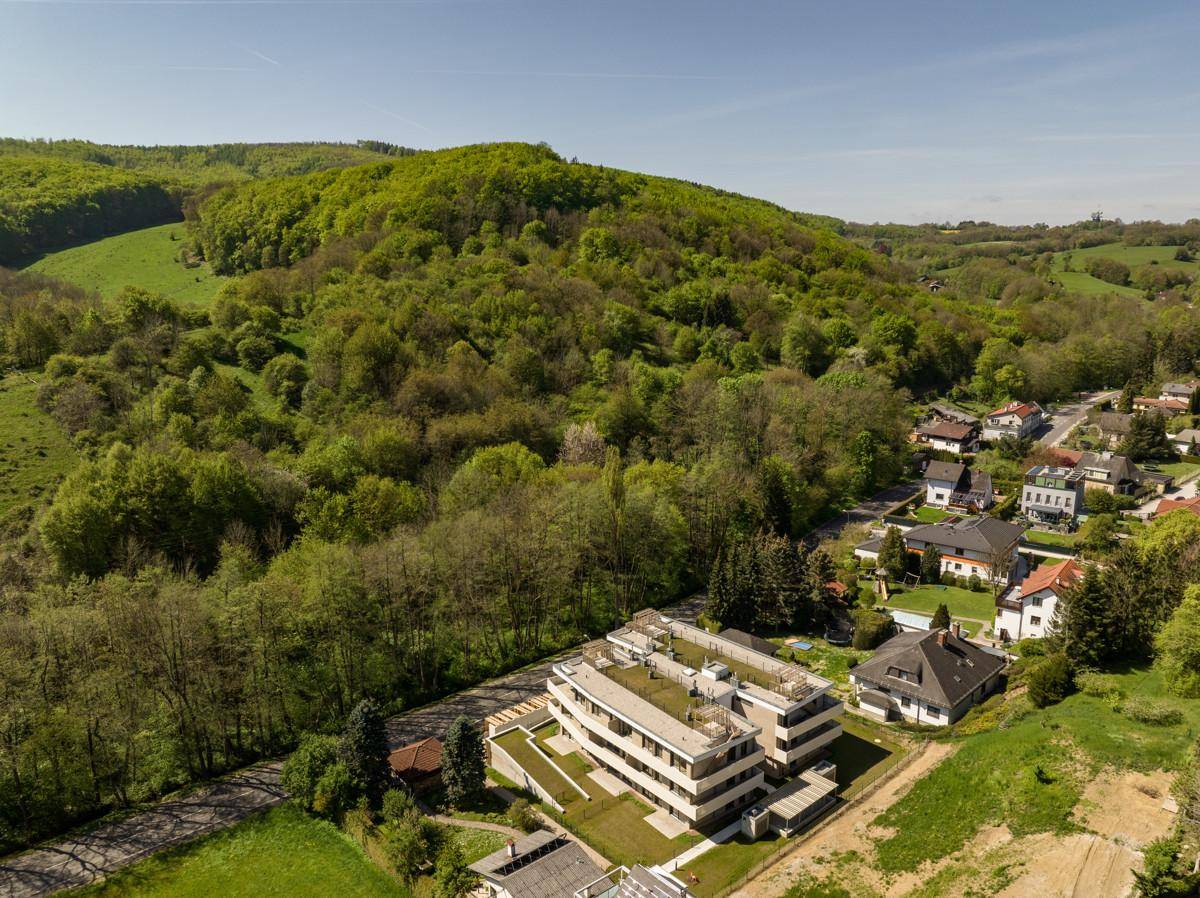 Weitläufige Luftaufnahme der Wohnanlage eingebettet in die grüne Hügellandschaft.