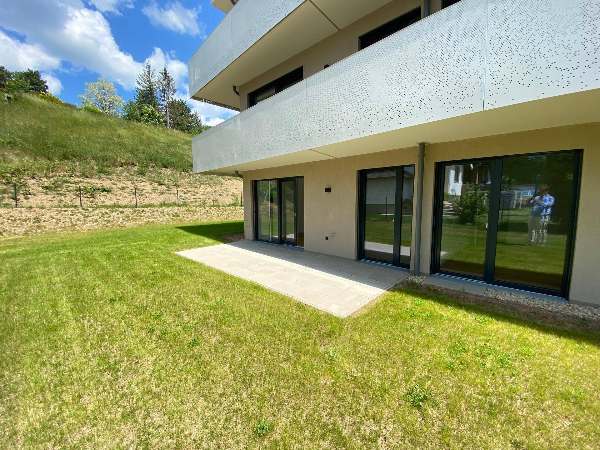 Erdgeschosswohnung mit direktem Zugang zur Terrasse und weitläufiger Rasenfläche am Hang.