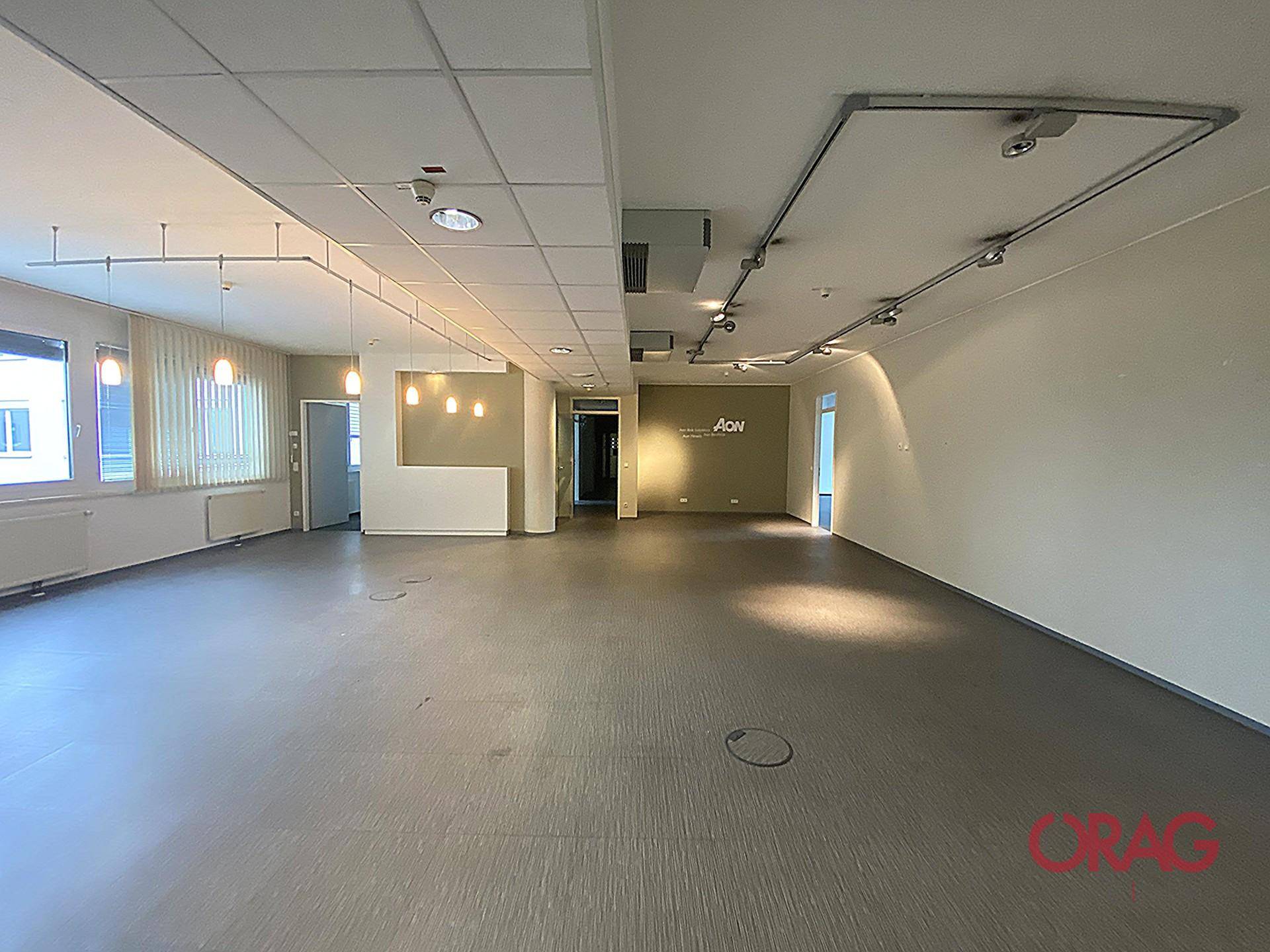 Offener Bürobereich mit Vinylboden und einer Wand mit Firmenlogo, ideal für ein modernes Arbeitsumfeld.