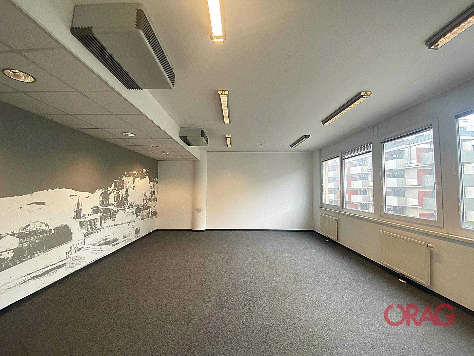 Bürofläche mit Teppichboden und einer dekorativen Wandgestaltung, ergänzt durch Klimaanlagen für angenehmes Raumklima.