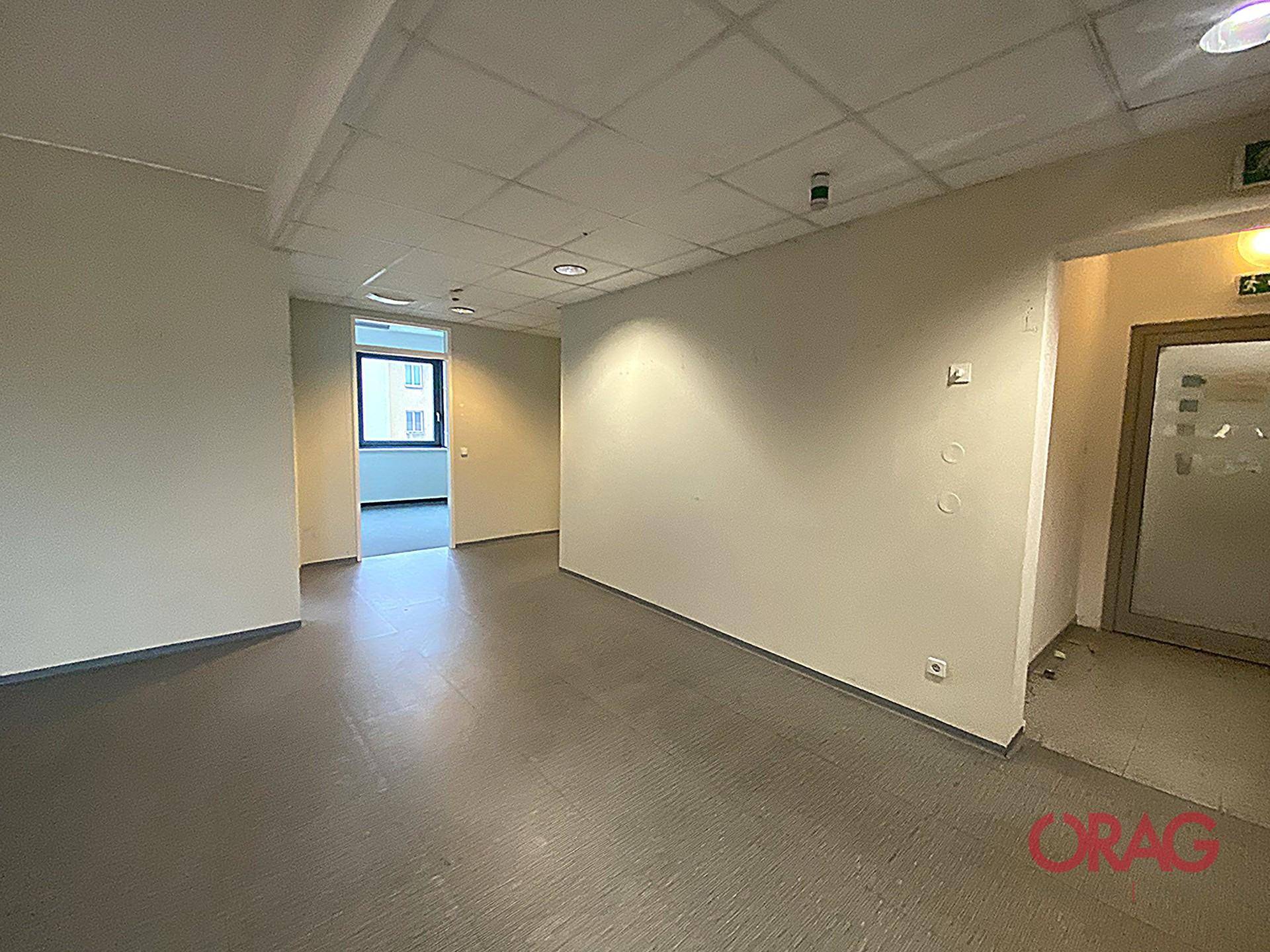 Langer Flur oder offener Bürobereich mit neutralen Wänden und praktischem Vinylboden, der zu weiteren Räumen führt.