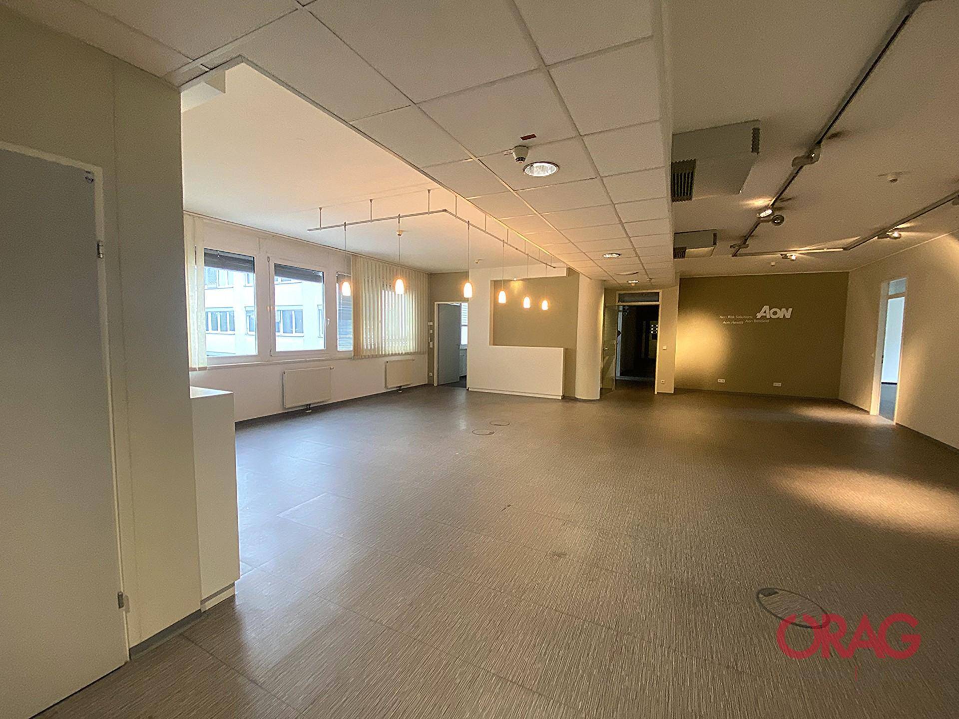 Weitläufiger Büroraum mit Vinylboden und einer Mischung aus natürlichem und künstlichem Licht, ideal für flexible Arbeitsbereiche.