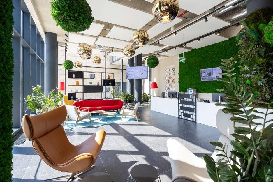 Stilvolle Lobby mit hohen Decken, bequemen Sitzgelegenheiten, einer Rezeption und dekorativen Pflanzen.