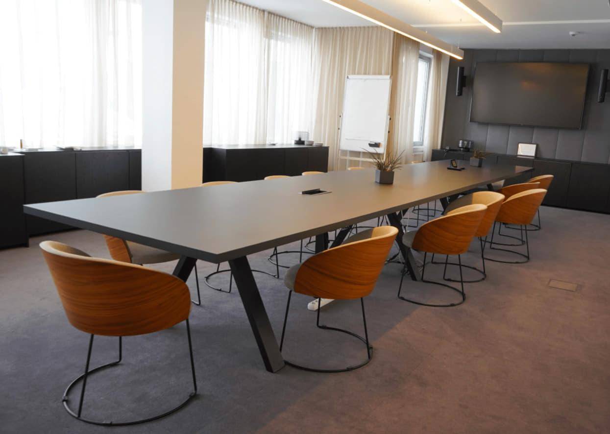 Großer Konferenzraum mit modernem Tisch, bequemen Stühlen und Präsentationstechnik für Besprechungen.