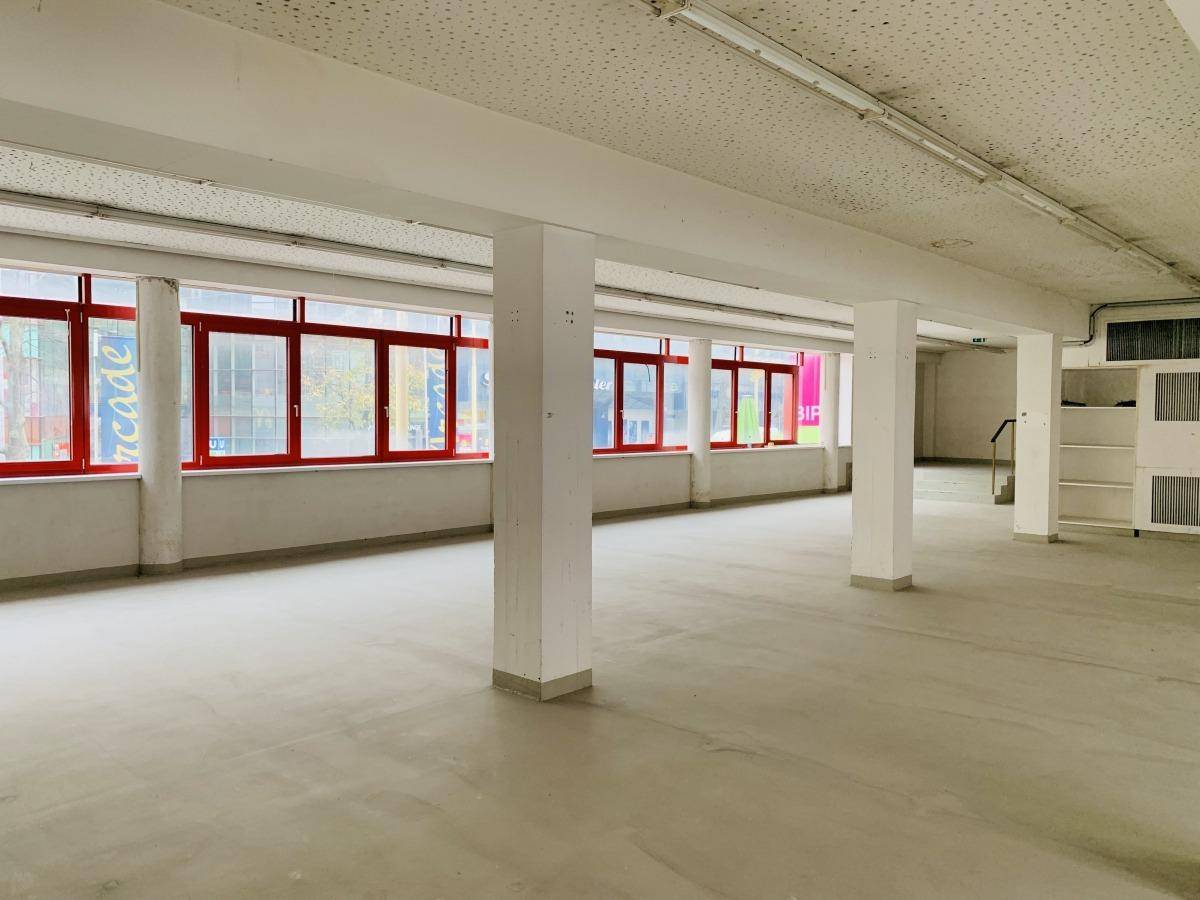 Großer, offener Gewerberaum mit vielen Fenstern und Säulen, bereit für den Ausbau.