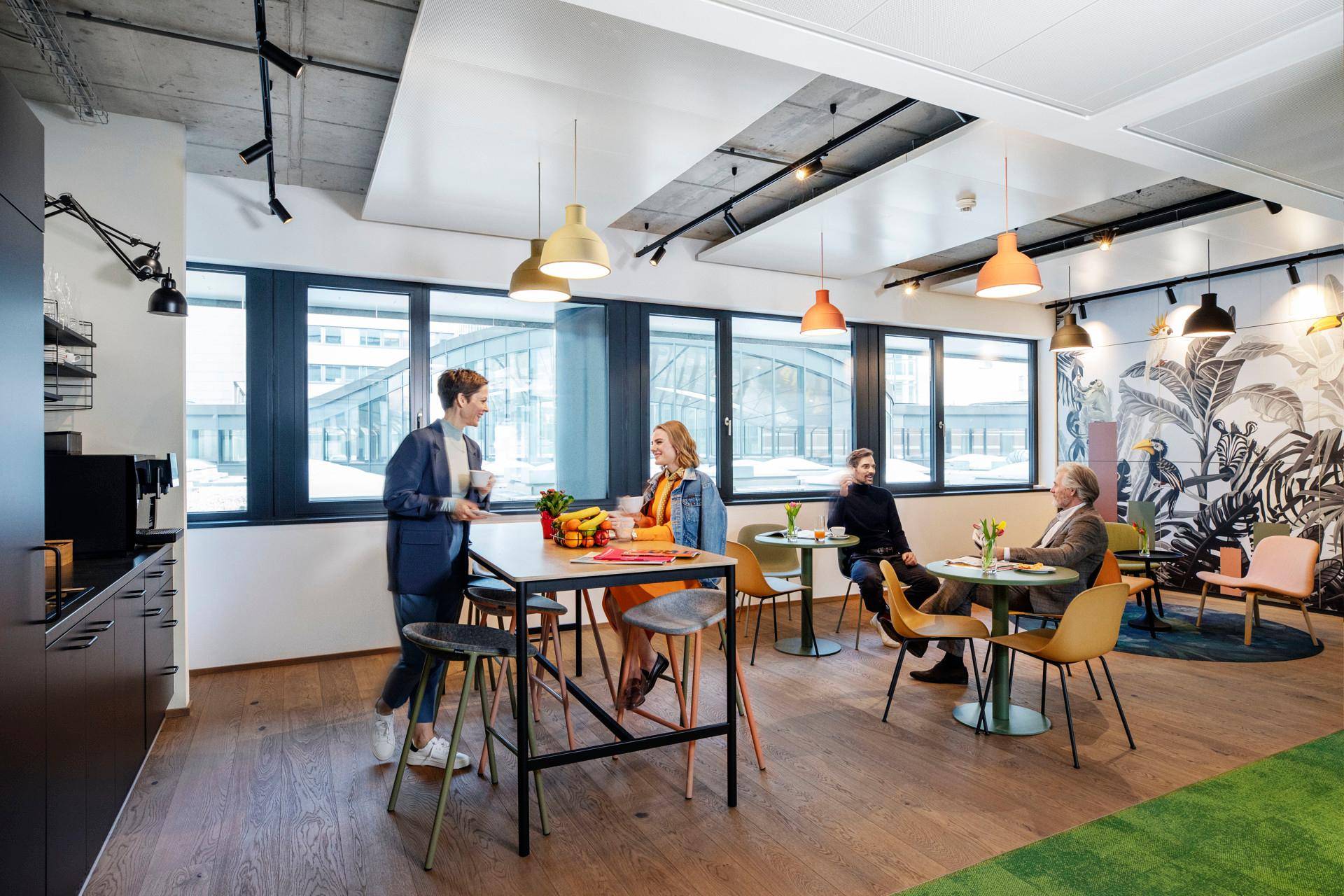 Gemütlicher Aufenthaltsbereich mit Holzboden, bunten Möbeln und großen Fenstern.