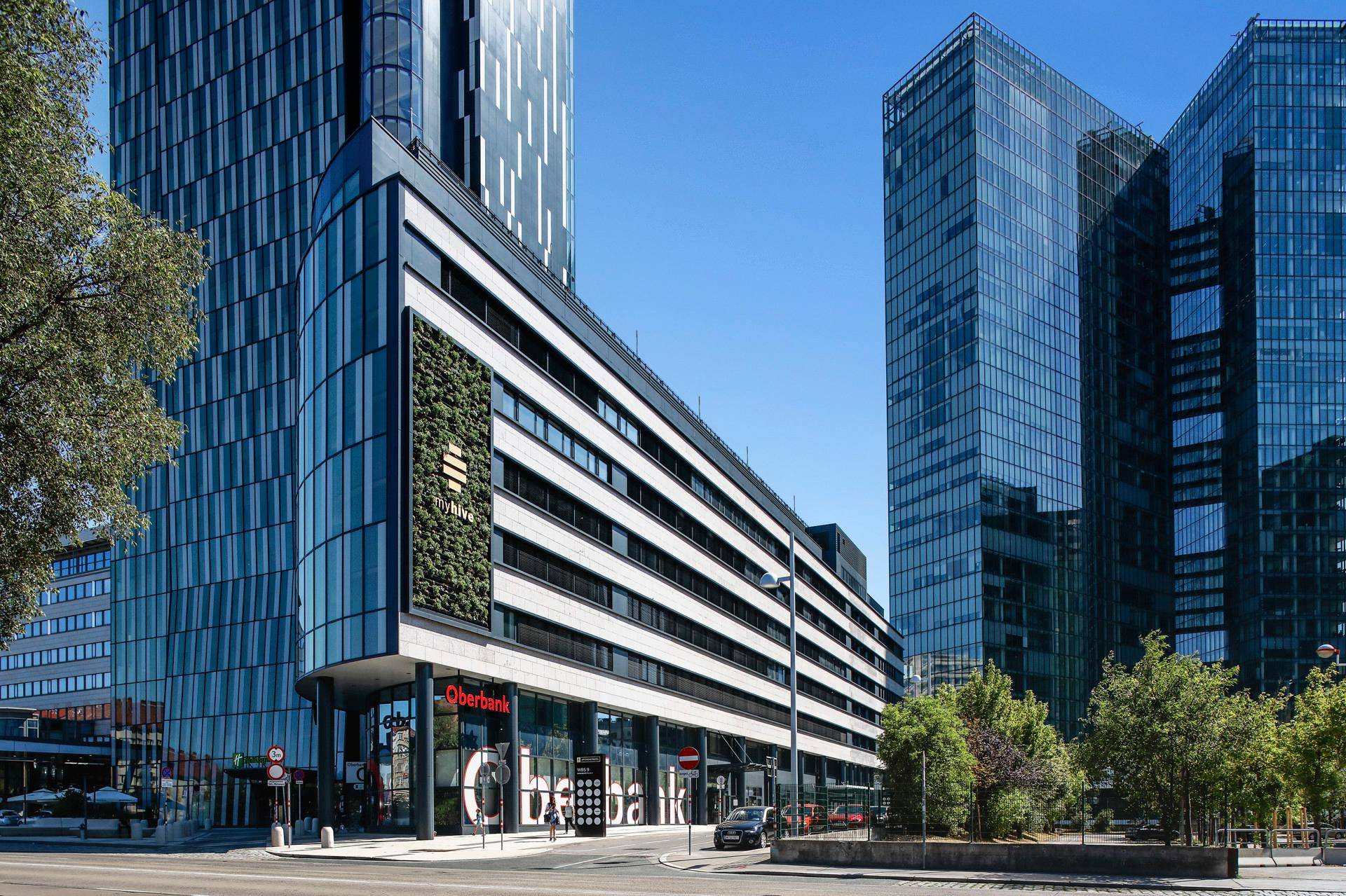 Moderne Bürogebäude mit Glasfassaden und vertikaler Begrünung in einer städtischen Umgebung.