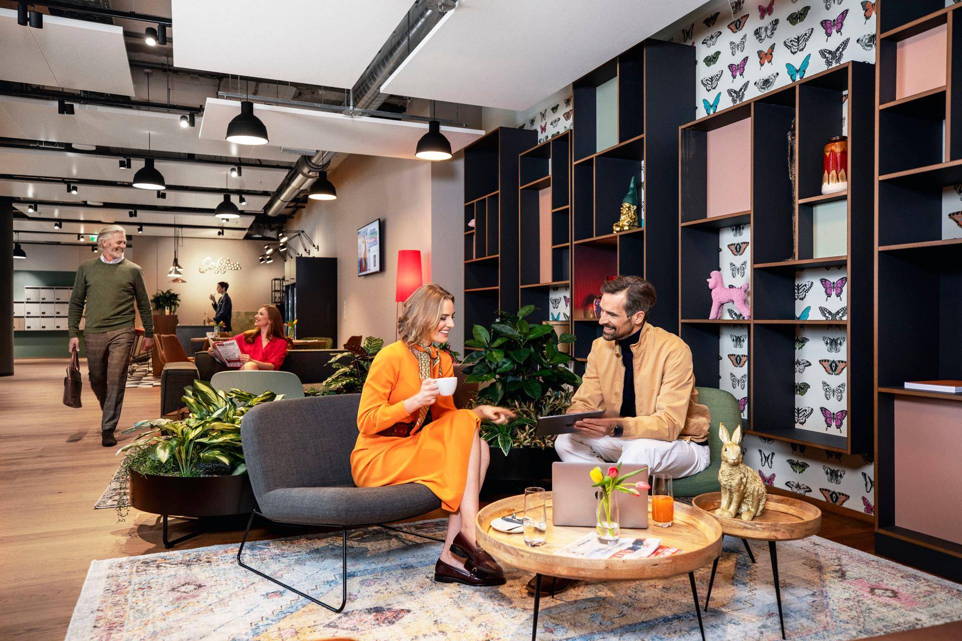 Gemütlicher Loungebereich mit bequemen Sofas, Holzboden und einem Bücherregal mit Schmetterlingsmuster.