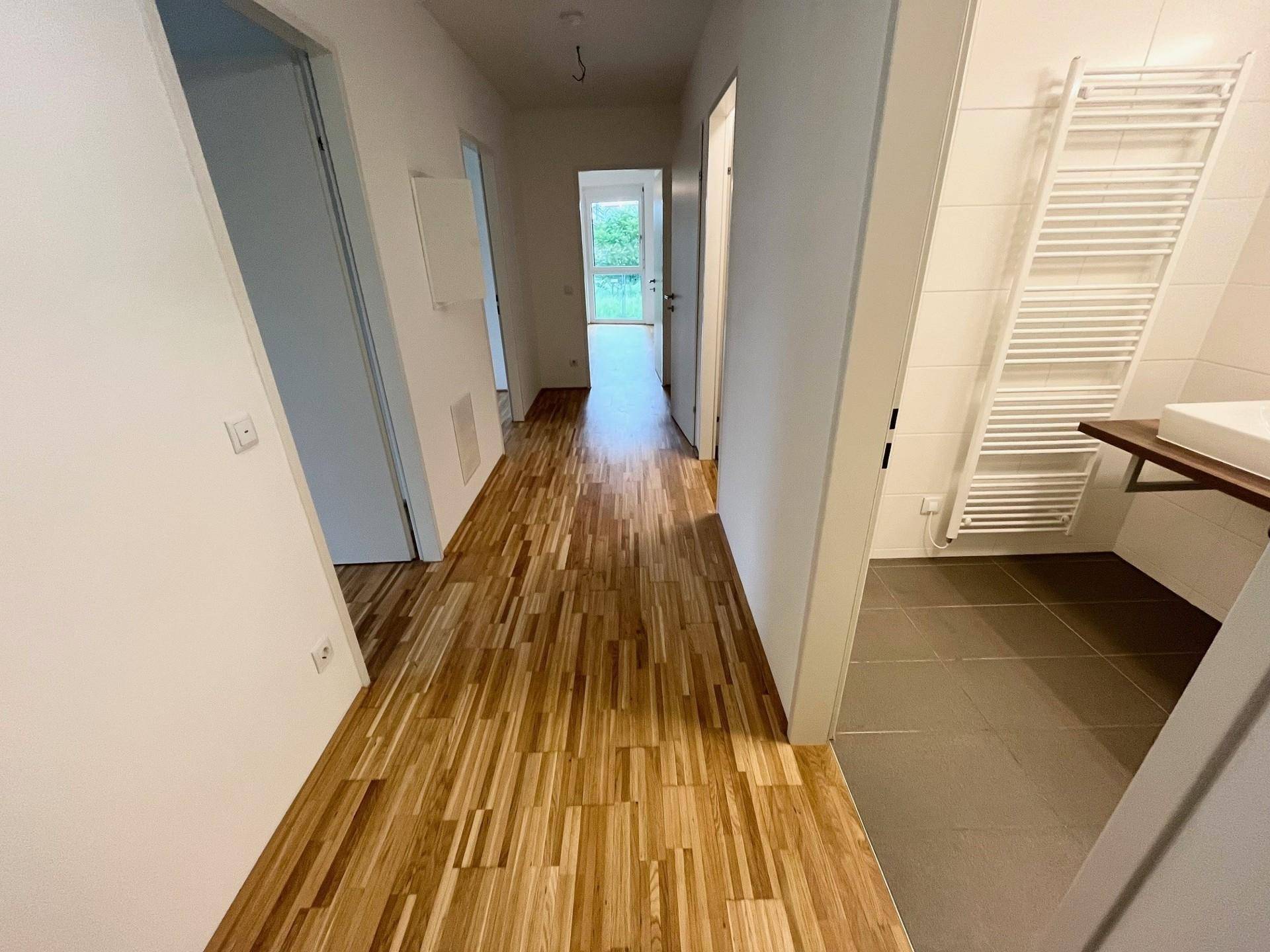 Langer Flur mit hellem Parkettboden, der zu verschiedenen Räumen führt.