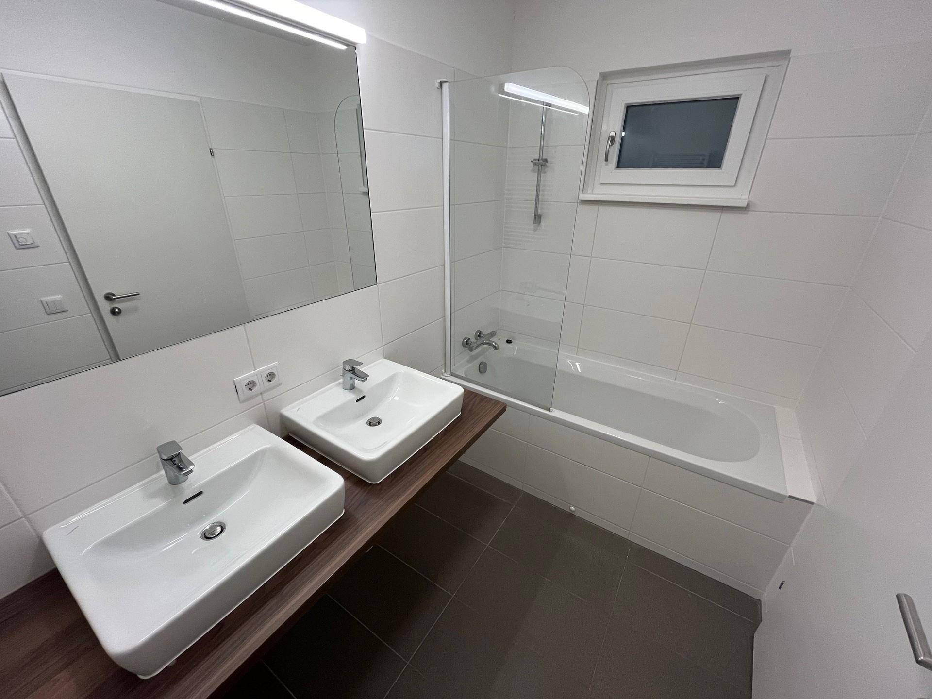 Modernes Badezimmer mit Doppelwaschbecken, Badewanne und beheiztem Handtuchhalter.