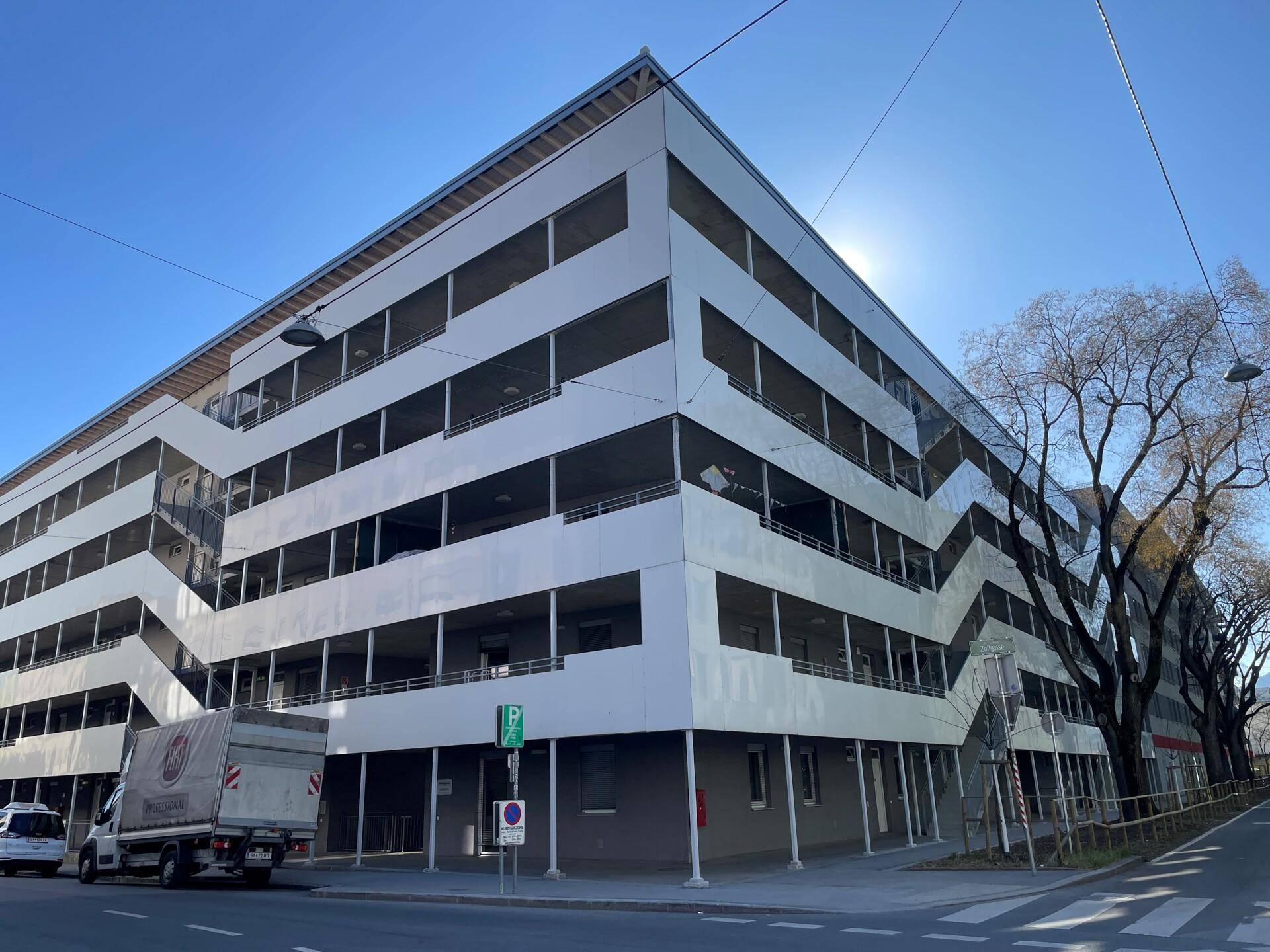 Großes Parkhaus mit mehreren Ebenen und moderner Architektur an einer städtischen Straße.
