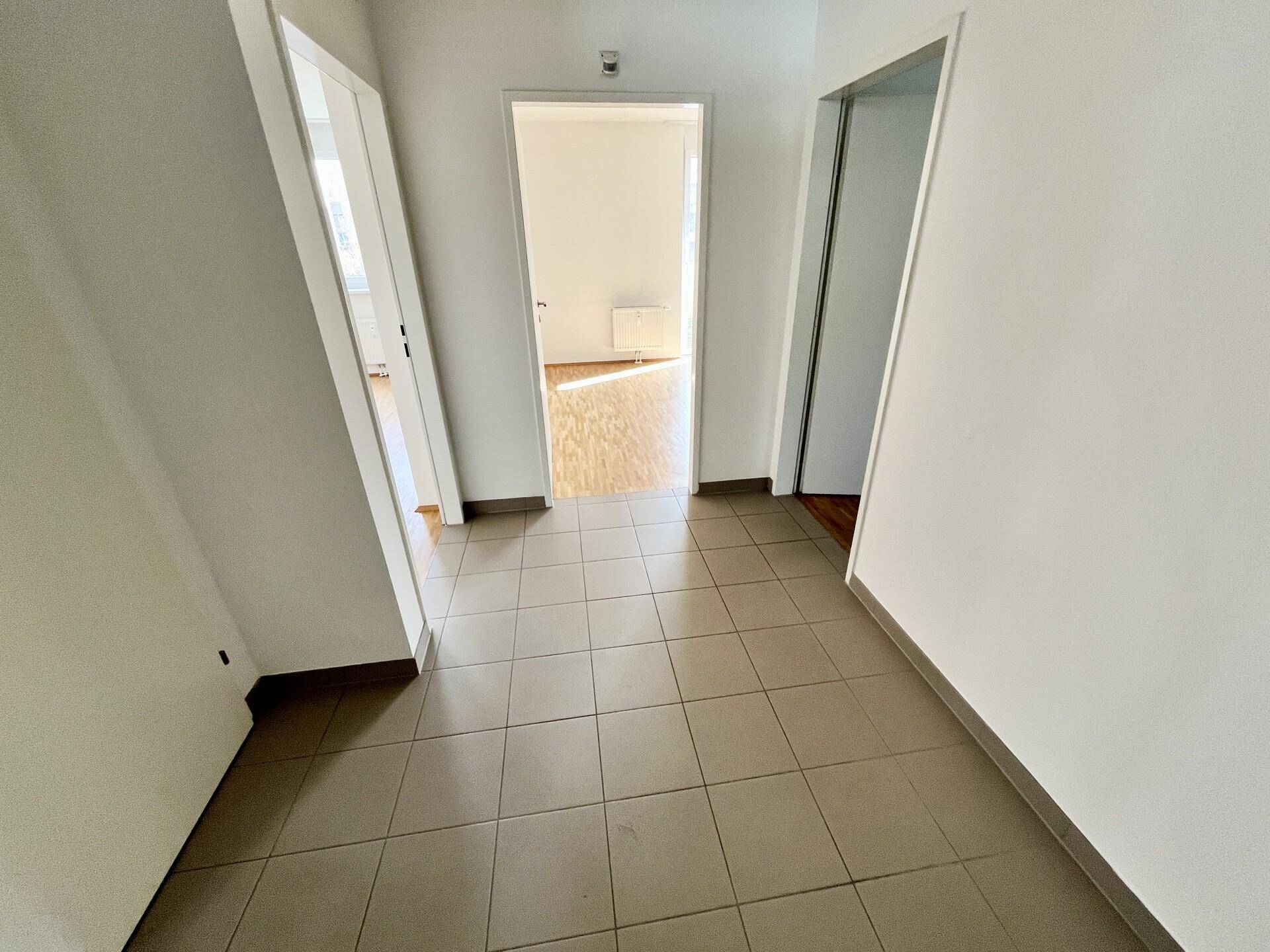 Heller Flur mit Fliesenboden und Zugang zu verschiedenen Räumen der Wohnung.