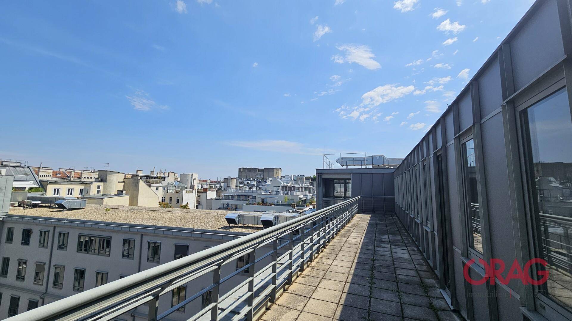 Lange Dachterrasse mit weitem Blick über die städtische Skyline und umliegende Gebäude.