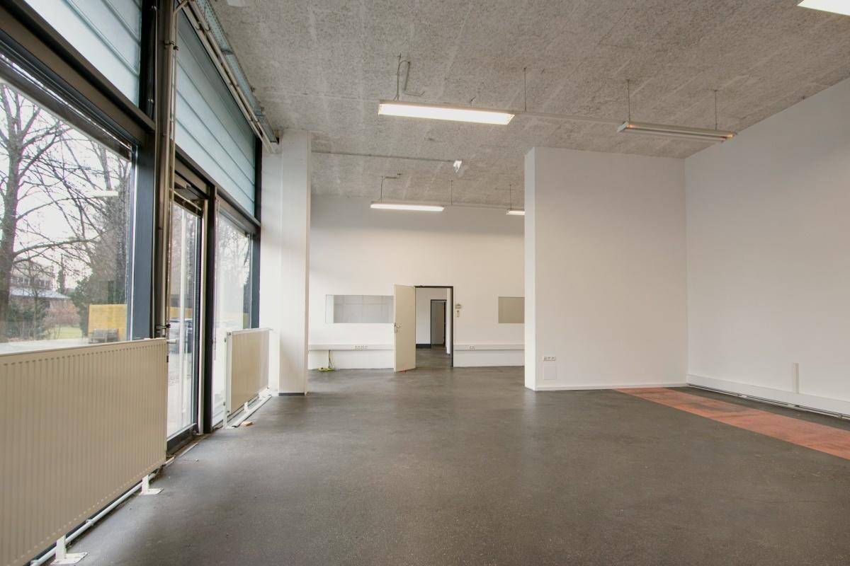 Heller Gewerberaum mit großen Fenstern, die viel Tageslicht hereinlassen, und einem robusten Boden.