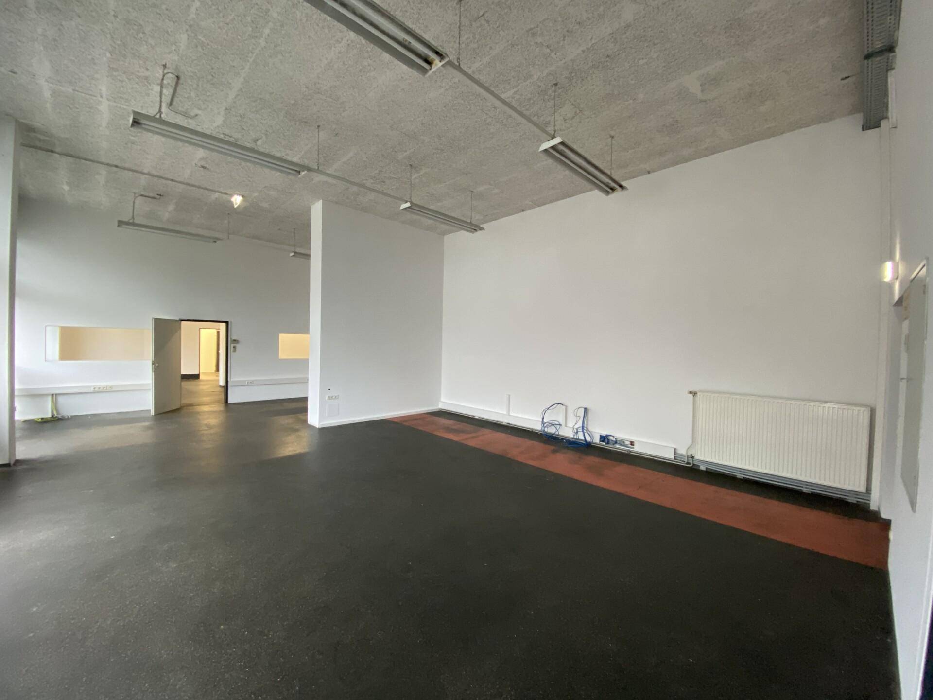 Geräumiger Gewerberaum mit Betonboden und weißen Wänden, bereit für die individuelle Gestaltung.