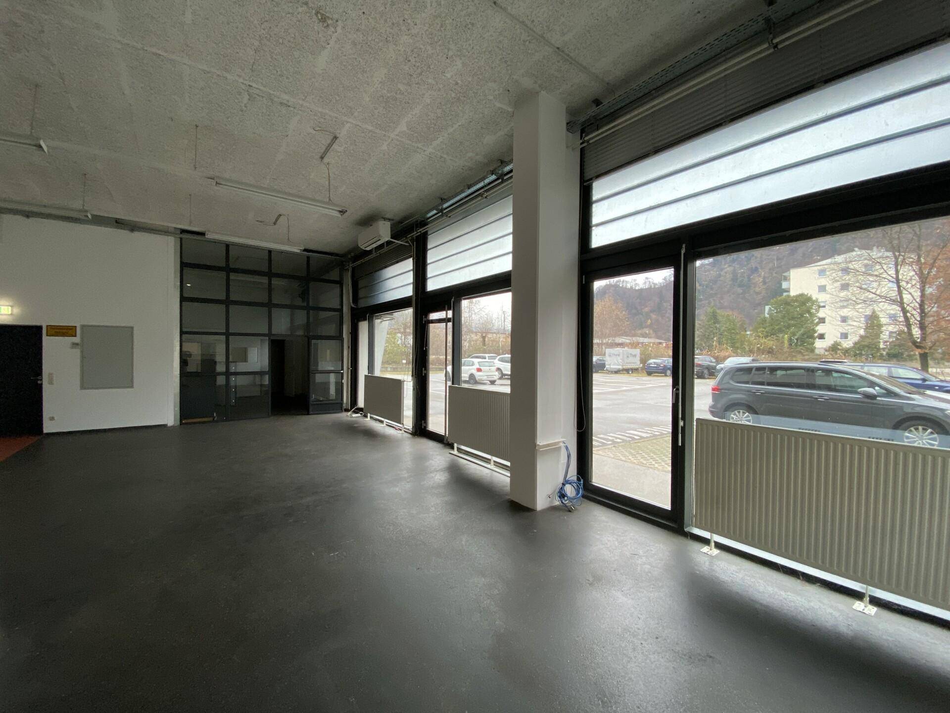 Heller Gewerberaum mit großen Fenstern und Blick auf den Außenbereich, mit viel Tageslicht.