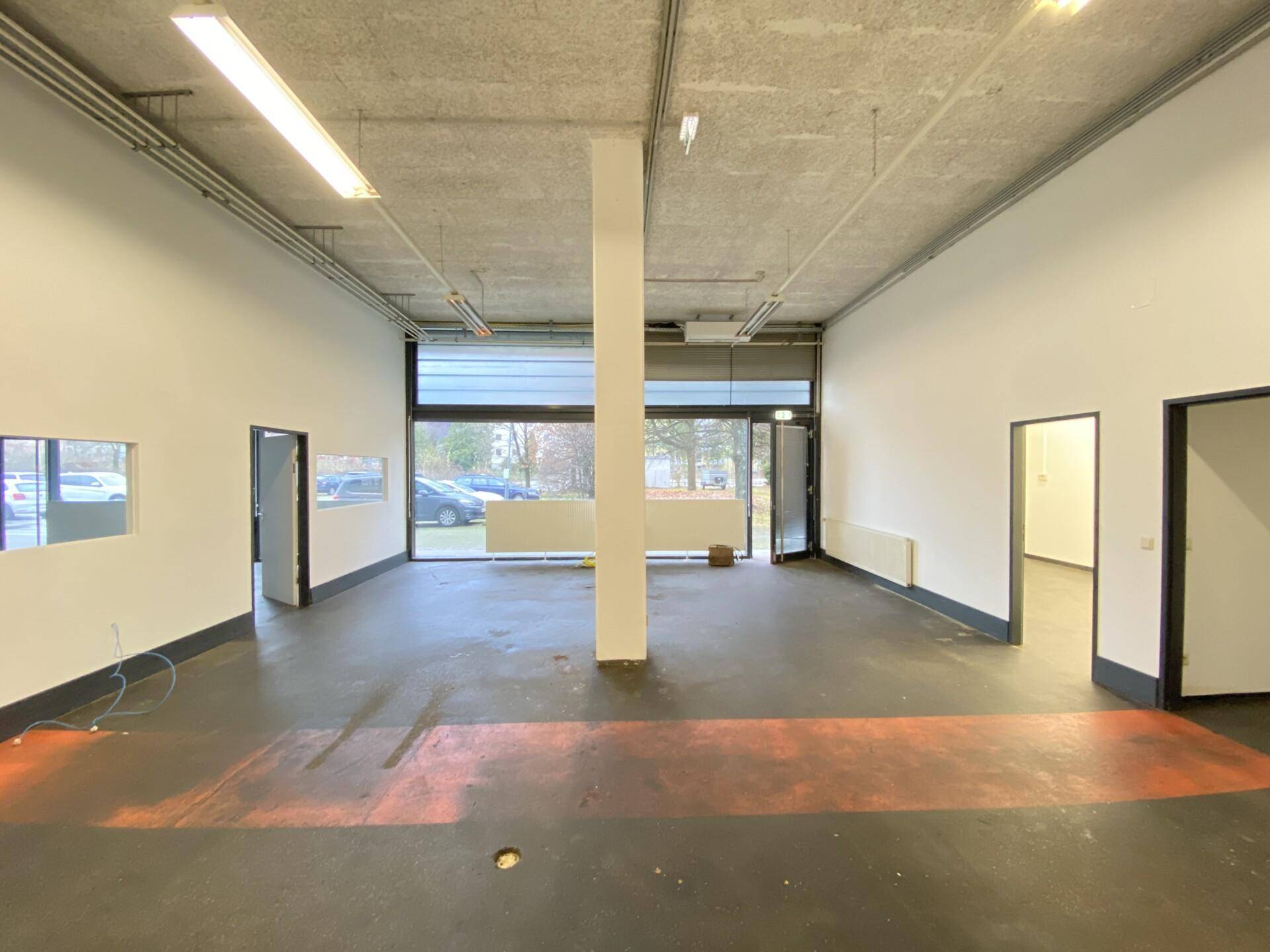 Geräumiger, leerer Büroraum mit großen Fenstern und Blick auf den Außenbereich.