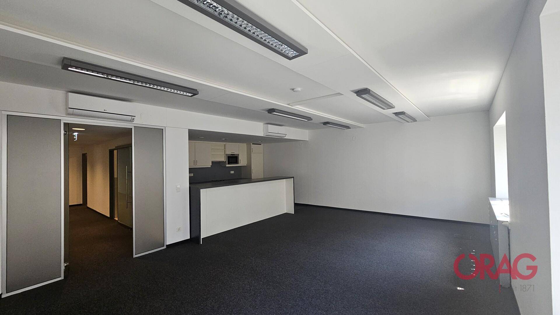 Geräumiges Büro mit integrierter moderner Küchenzeile, Teppichboden und Klimaanlage, ideal für Pausen.