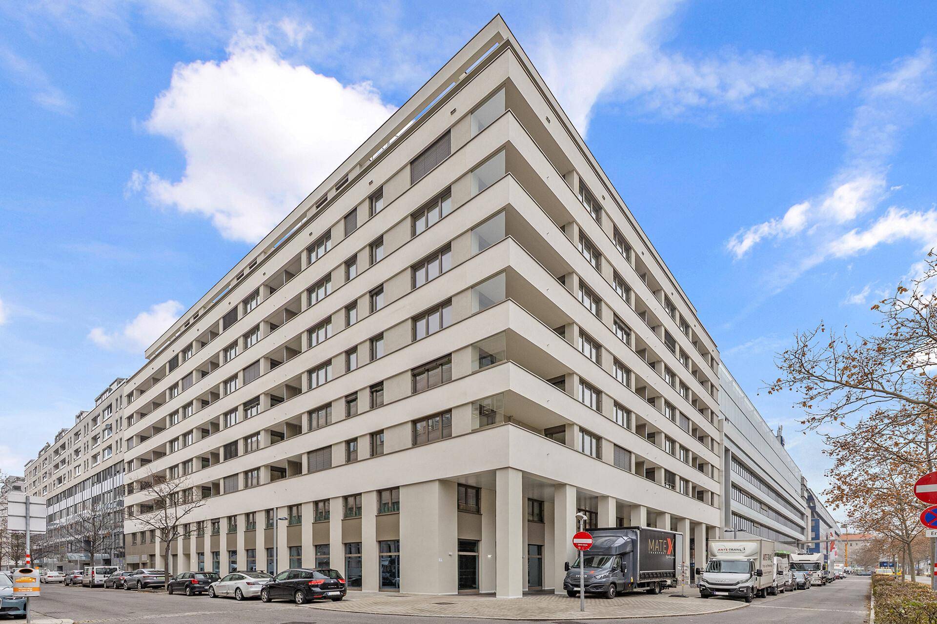 Großes, modernes Wohn- und Geschäftsgebäude mit vielen Balkonen und klarer Architektur in städtischer Umgebung.