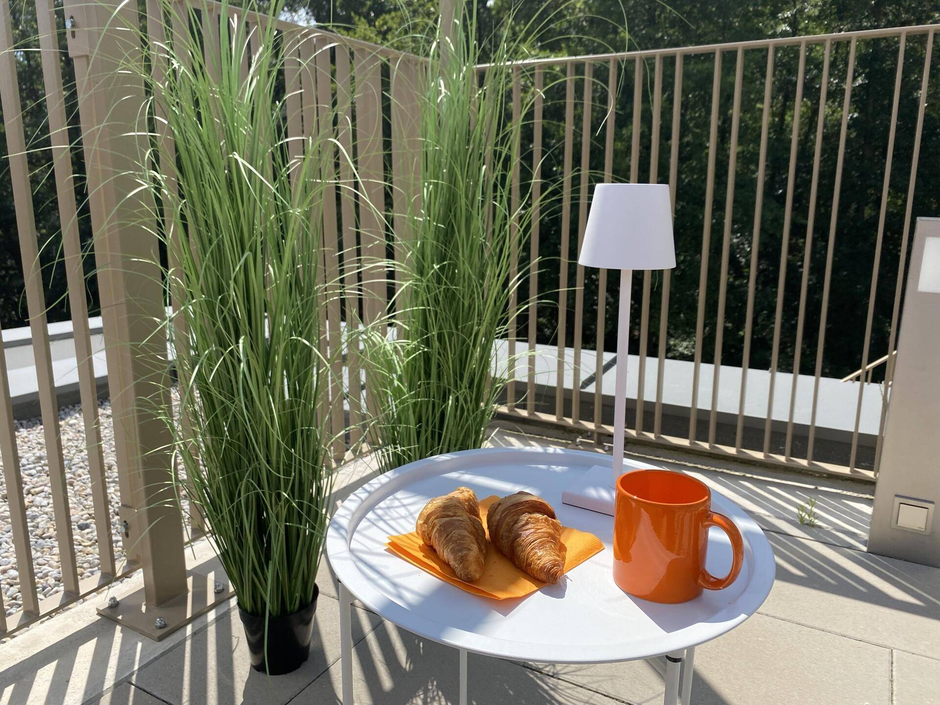 Gemütlicher Frühstücksbereich auf der Terrasse mit einem kleinen Tisch und Blick ins Freie.