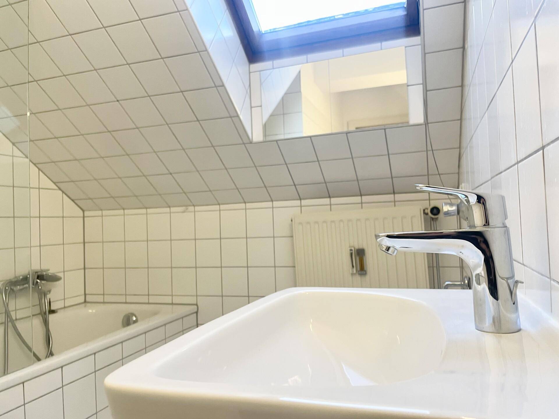 Modernes Badezimmer mit Badewanne, Waschbecken und Dachfenster für natürliches Licht.