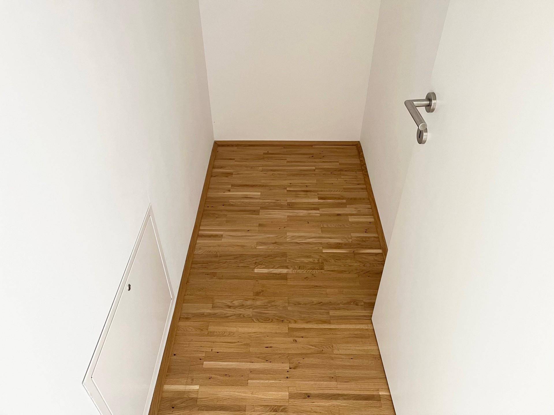 Heller Flur mit Holzparkettboden und weiß gestrichenen Wänden, bietet Zugang zu weiteren Räumen.