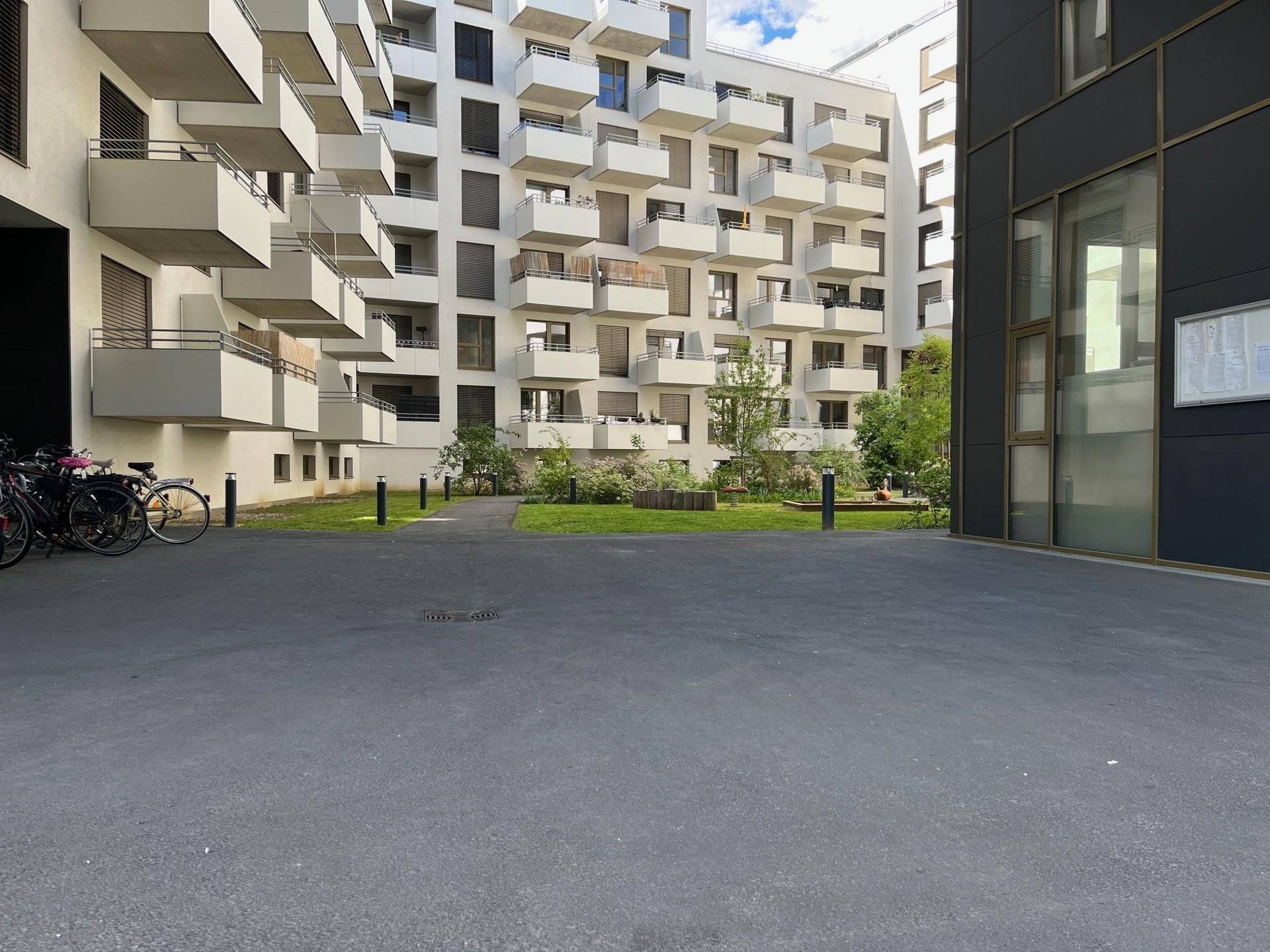 Innenhof eines modernen Wohnkomplexes mit Grünflächen und Fahrradabstellplätzen.
