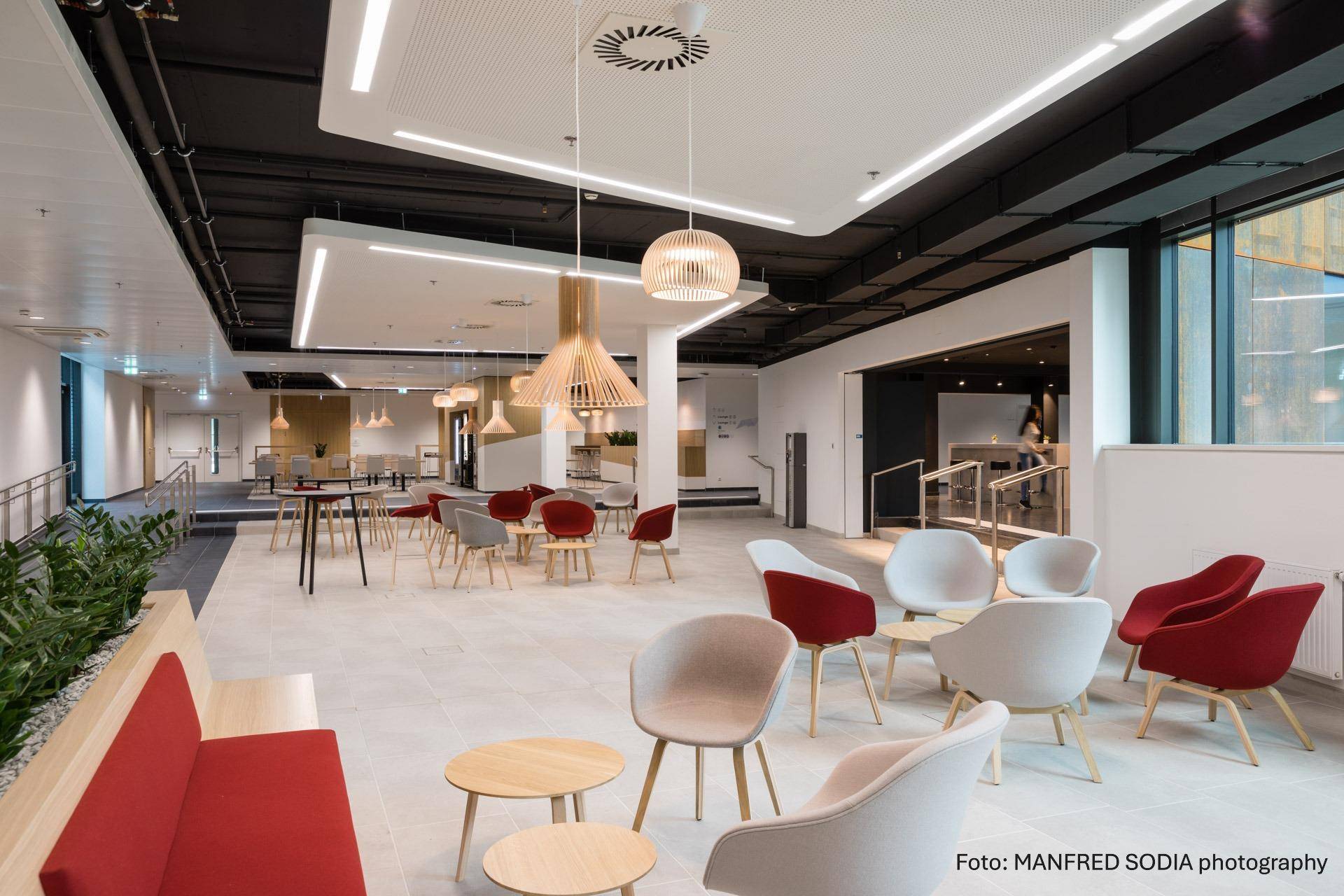 Geräumiger, moderner Loungebereich mit vielfältigen Sitzgelegenheiten und stilvollen Pendelleuchten.