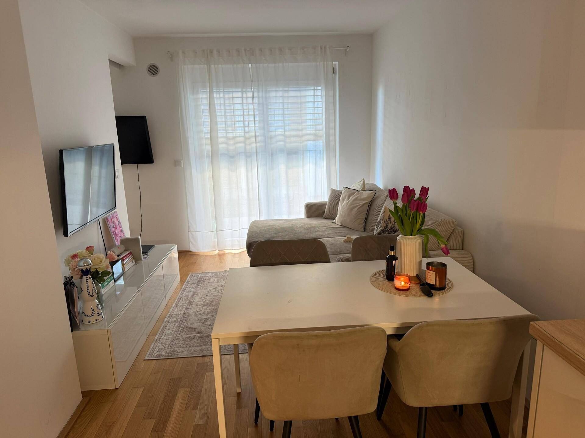 Gemütlicher Wohnbereich mit Sofa, Esstisch und großen Fenstern für viel Tageslicht.