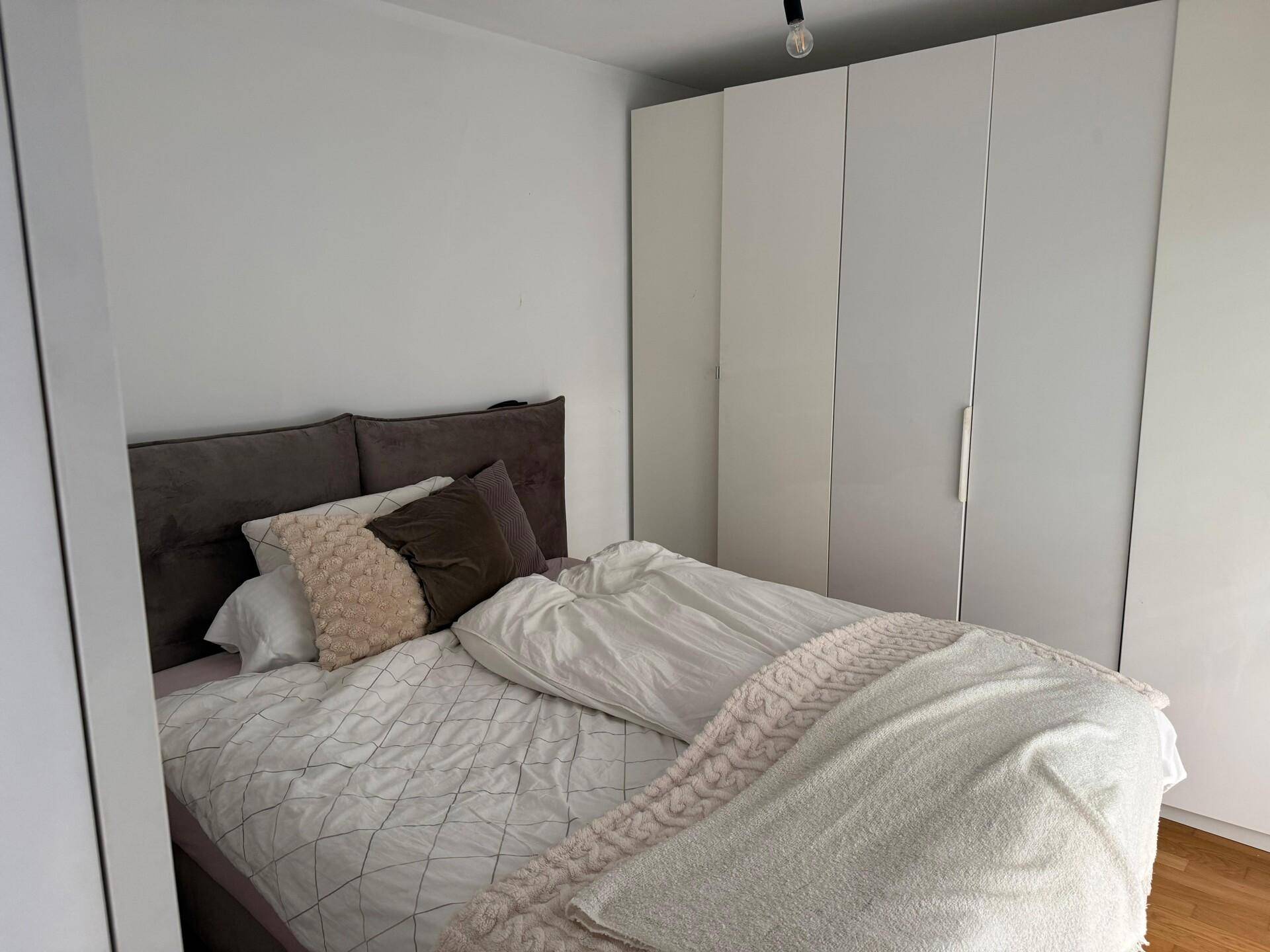 Schlafzimmer mit großem Bett, Einbauschränken und hellem Ambiente.