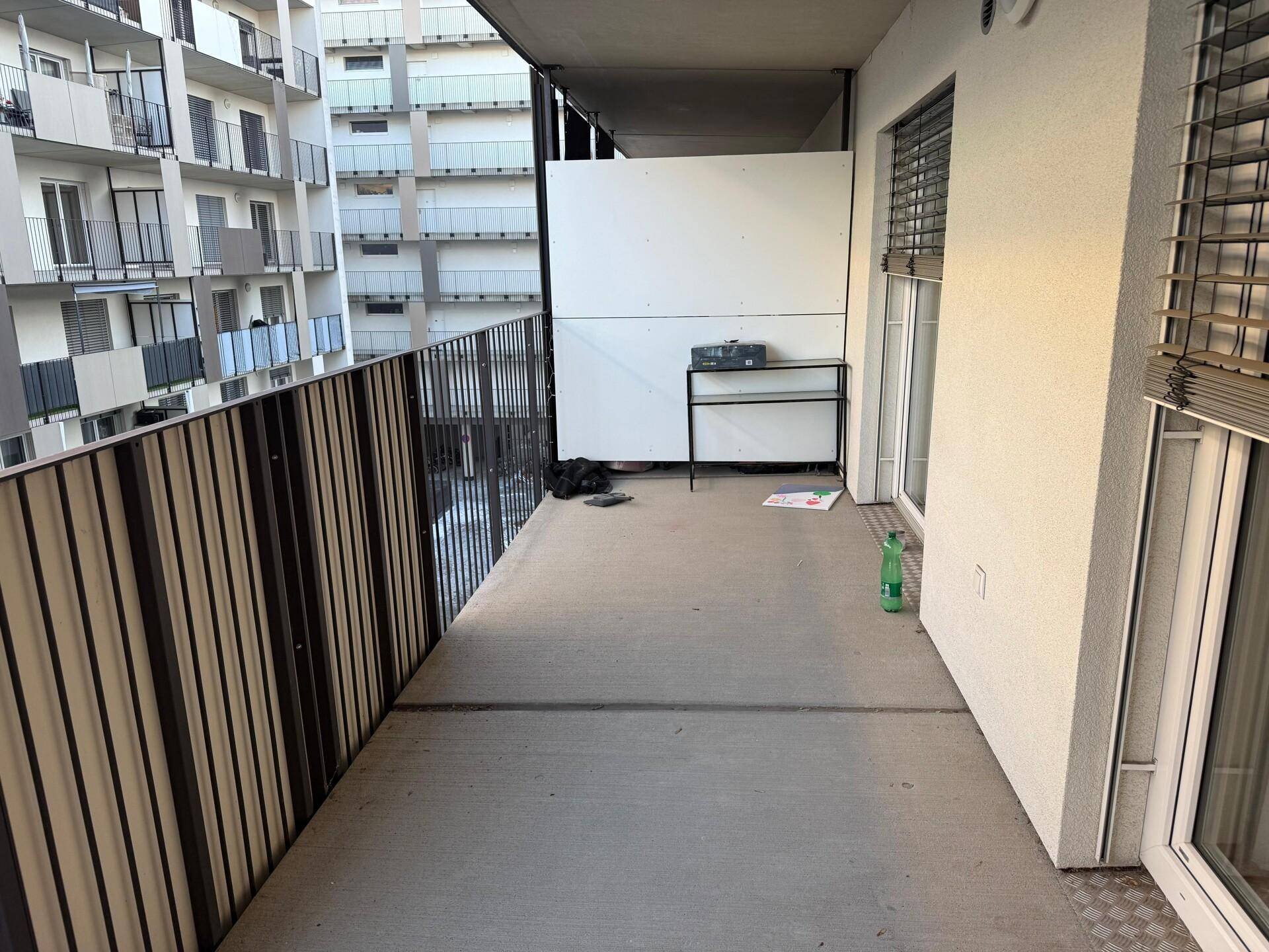 Geräumiger Balkon mit Metallgeländer und Blick auf die umliegenden Gebäude.
