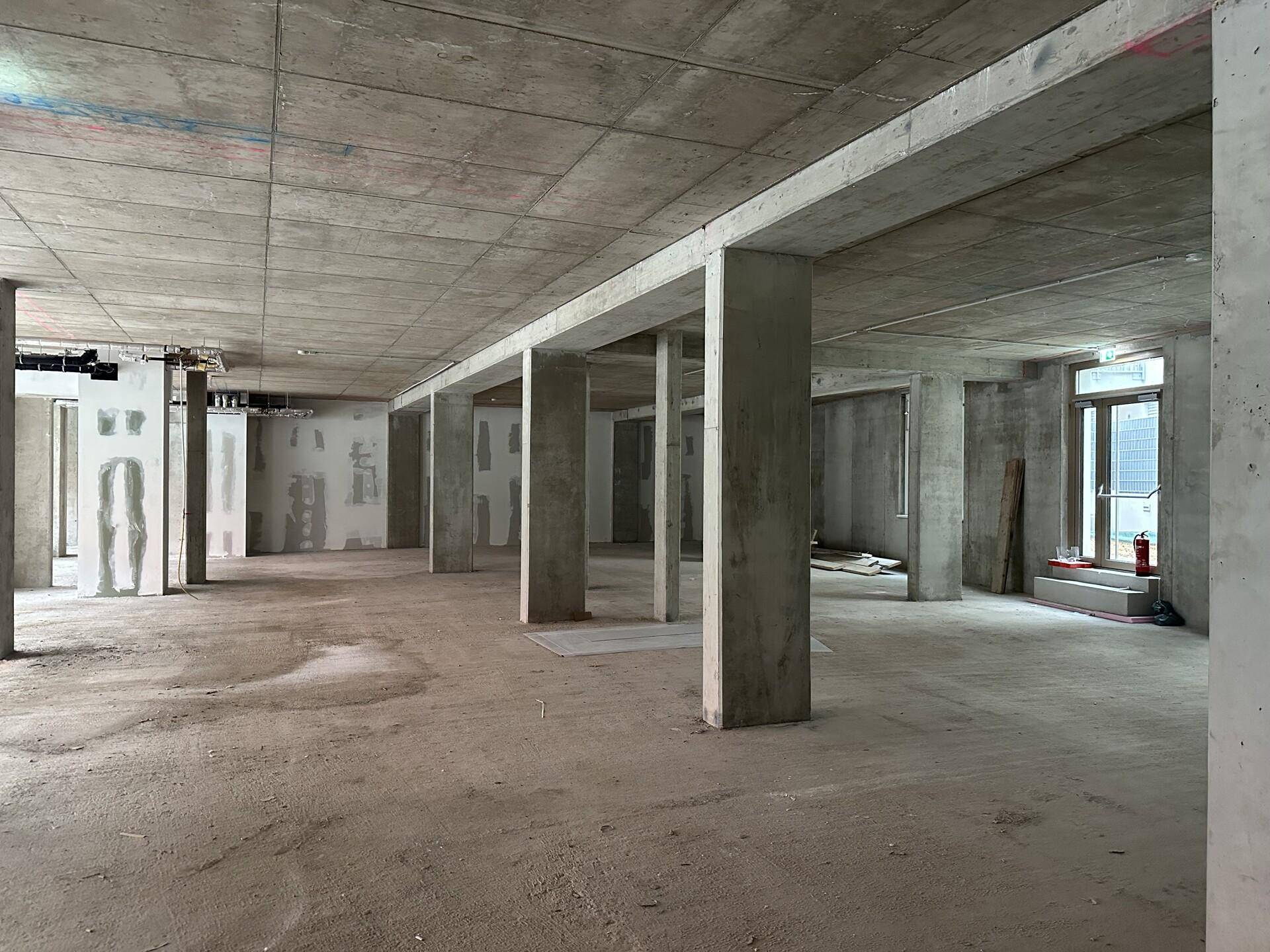 Weitläufiger Rohbau-Raum mit Betonstützen und Decken, bereit für den Innenausbau.