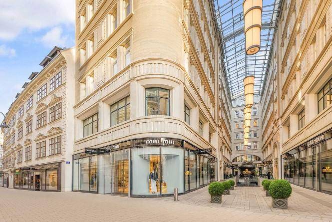 Elegantes Geschäftsgebäude mit klassischer Architektur, großen Schaufenstern und einer beeindruckenden Glasüberdachung.