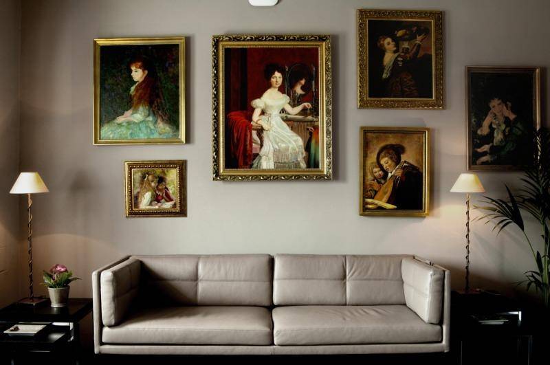Gemütlicher Wohnbereich mit beigem Sofa, klassischen Gemälden an der Wand und stimmungsvoller Beleuchtung.