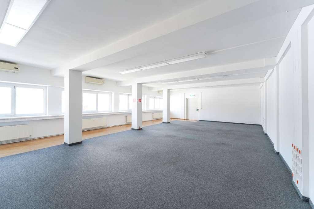 Großes, helles Büro mit Teppichboden, vielen Fenstern und Klimaanlagen an der Wand.