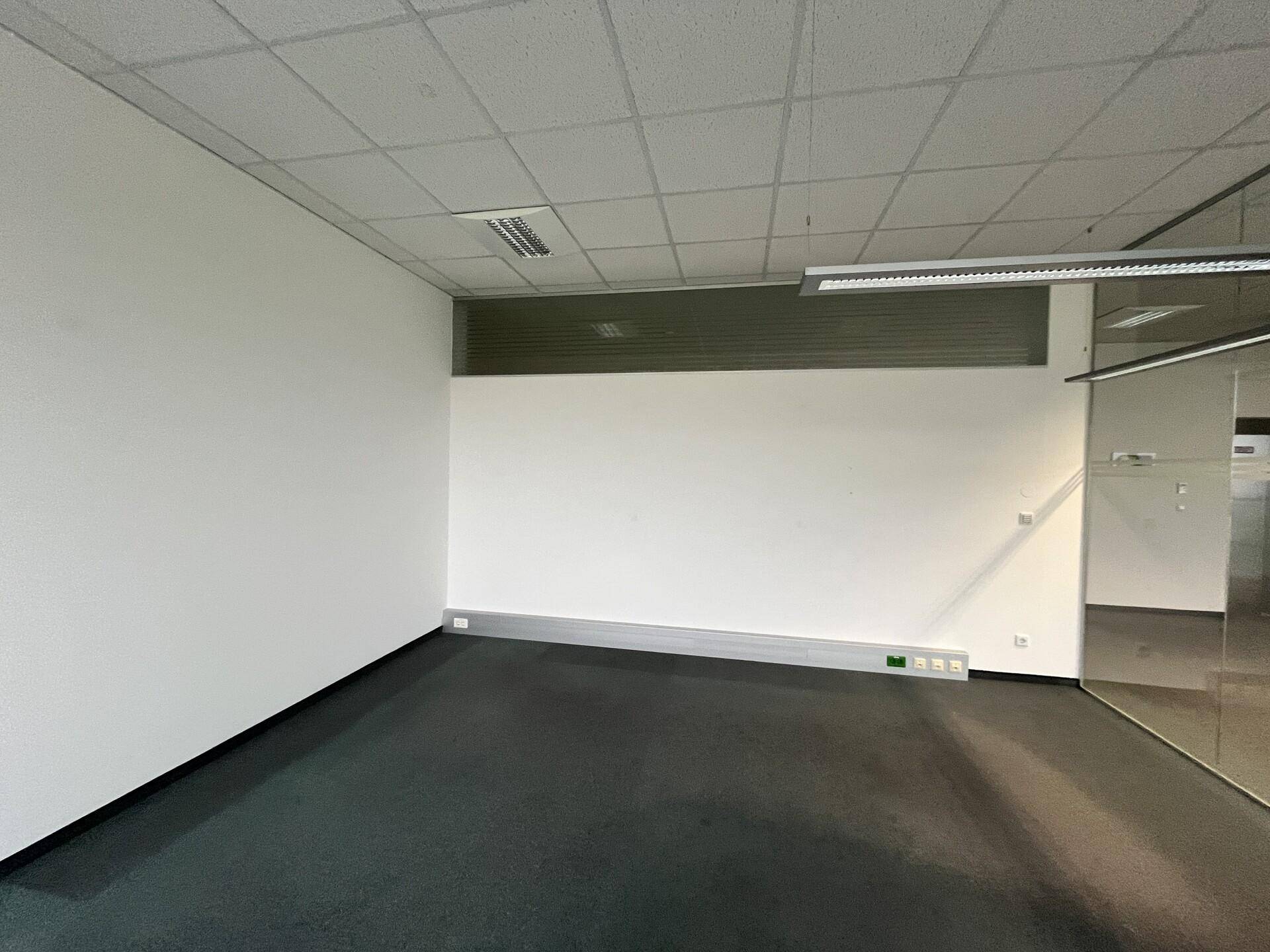 Leeres Büro mit Teppichboden und einer Glaswand, die den Raum optisch erweitert.
