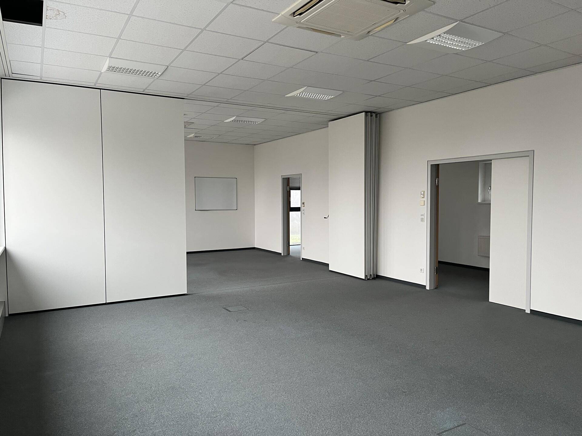 Großes, flexibles Büro mit Teppichboden und verschiebbaren Trennwänden, ideal für verschiedene Arbeitsbereiche.