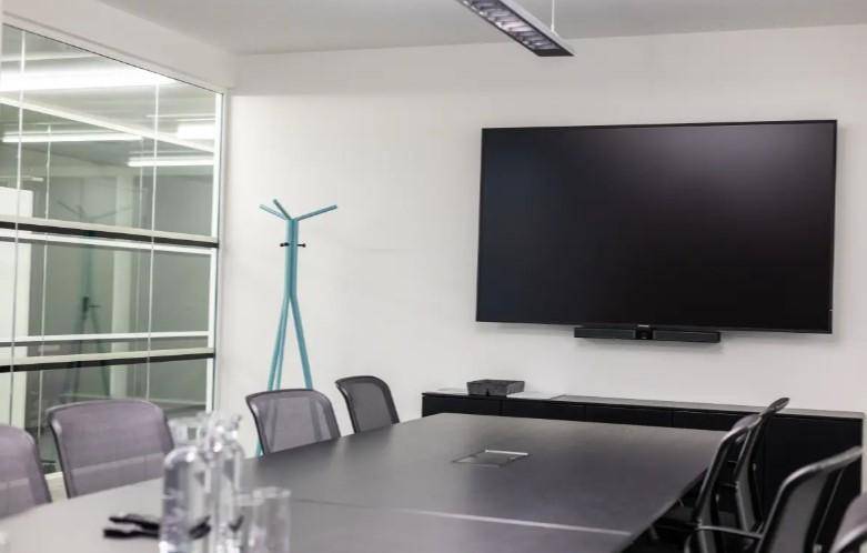 Funktionaler Konferenzraum mit großem Wandfernseher, langem Tisch und modernen Stühlen für Besprechungen.