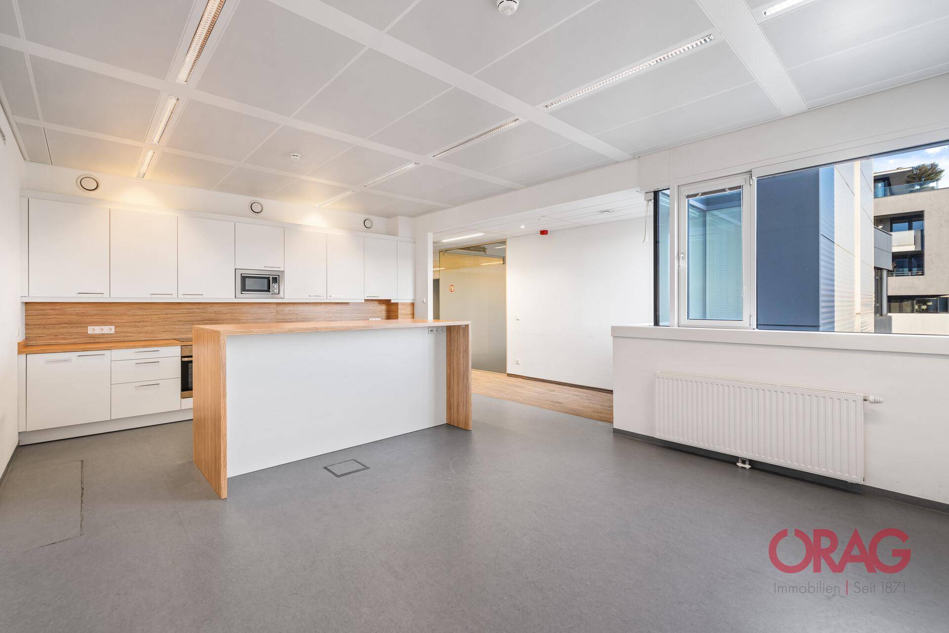 Moderne Büroküche mit weißen Schränken, Holzarbeitsplatten und einer Kücheninsel.