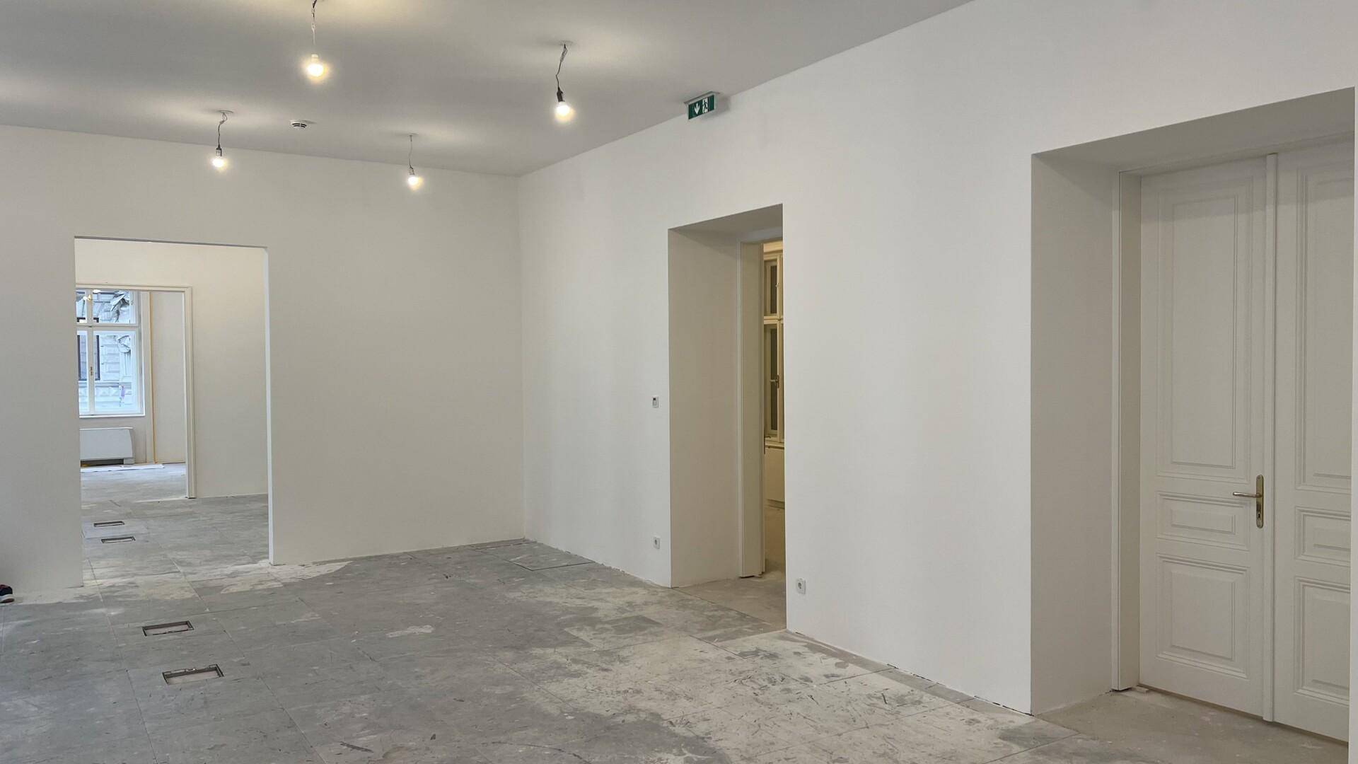 Heller, leerer Raum mit weißen Wänden, hohen Decken und traditionellen Türen, bereit zur individuellen Gestaltung.