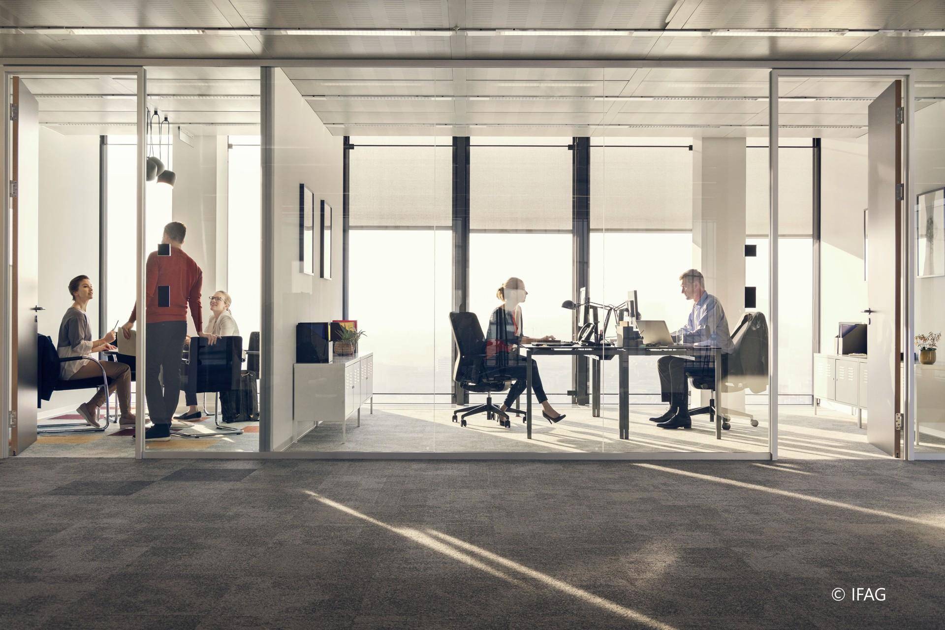 Helle Büroräume mit Glaswänden, die separate Arbeitsbereiche und viel Tageslicht bieten.