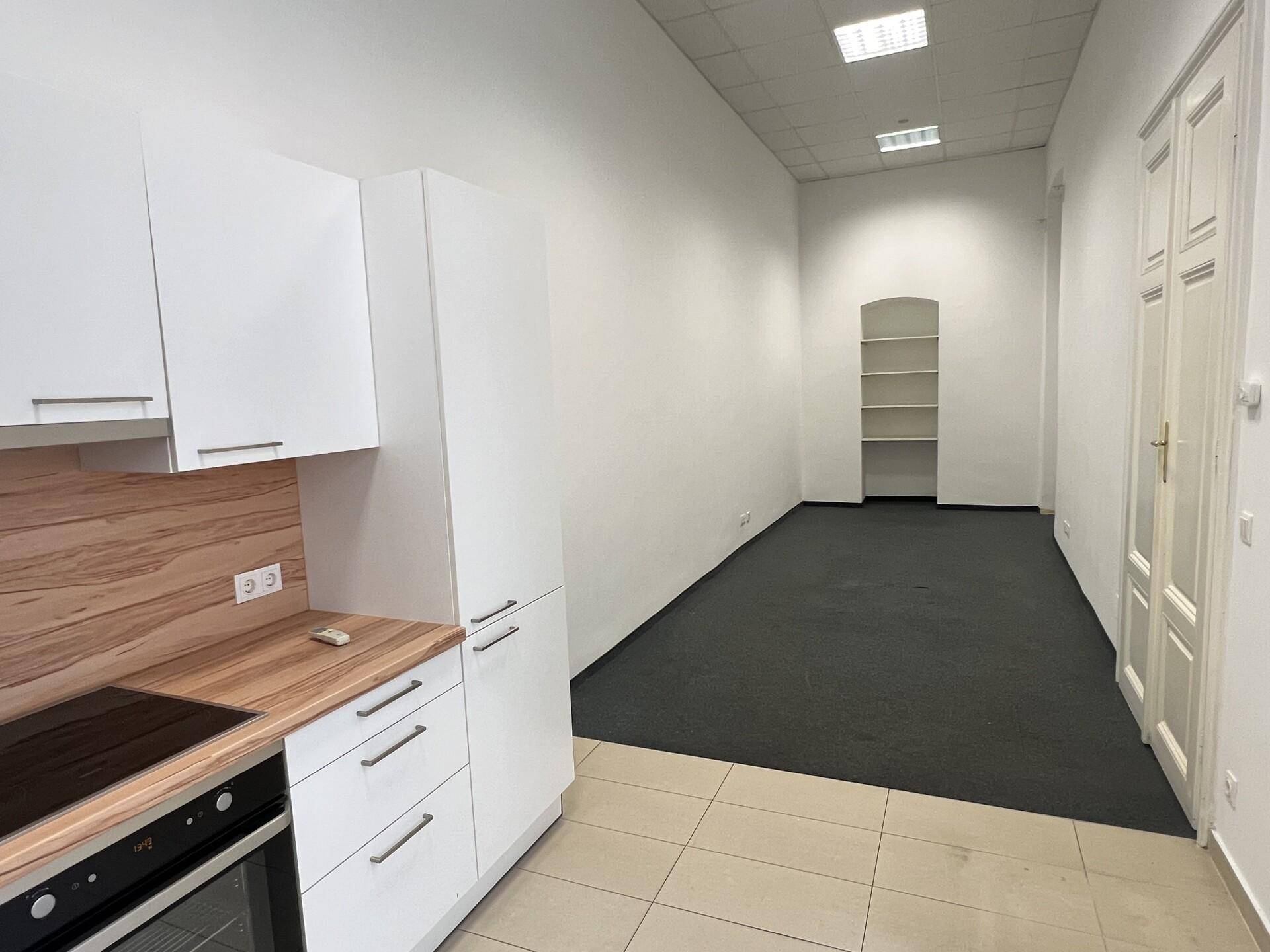 Offener Bereich mit moderner Küche, Fliesenboden und angrenzendem Raum mit Teppichboden, ideal für Wohnen und Kochen.