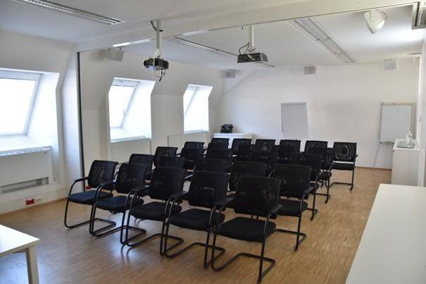 Schulungsraum mit Reihenbestuhlung, Projektoren und Dachfenstern für Präsentationen.