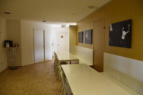 Langer Flur mit Sitzgelegenheiten und Kunstwerken an der Wand, ideal für Pausen.