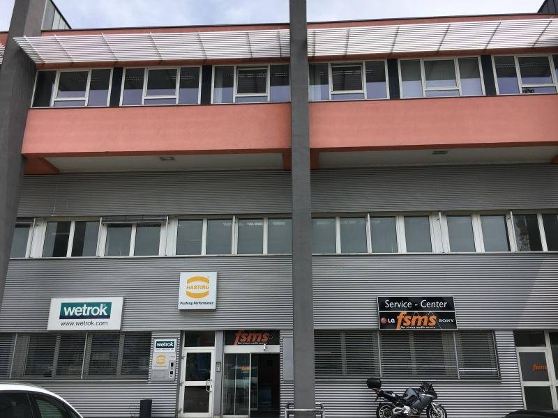 Ansicht eines modernen Bürogebäudes mit mehreren Etagen, großen Fenstern und Firmenbeschilderung.