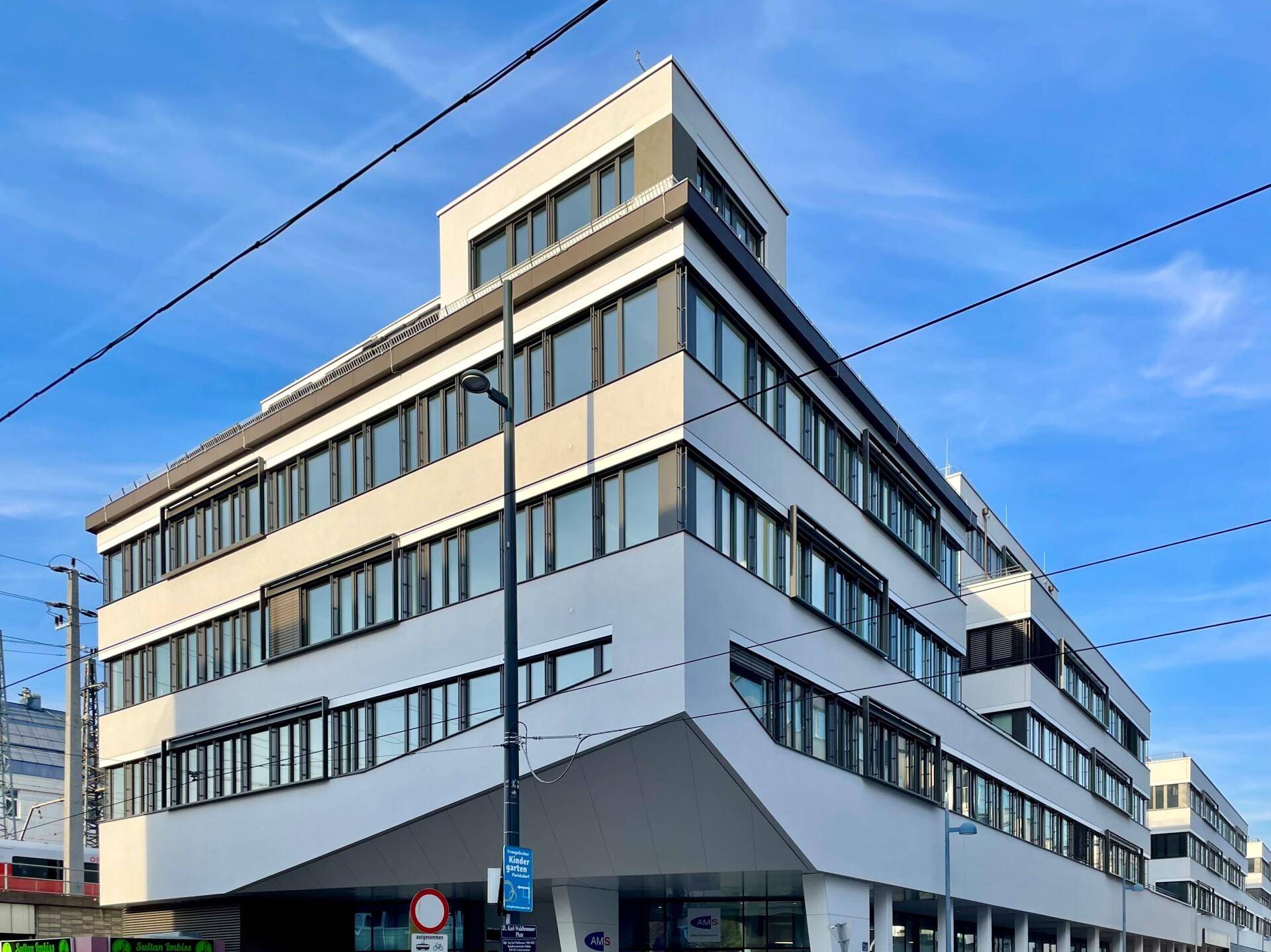 Modernes Geschäftsgebäude mit markanter Architektur, vielen Fenstern und klaren Linien unter blauem Himmel.