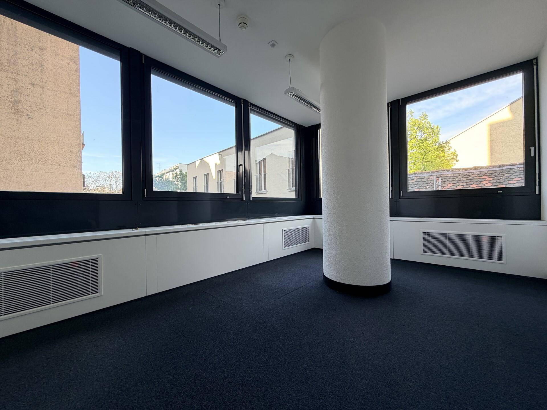 Großes Eckbüro mit vielen Fenstern, die viel Tageslicht hereinlassen, und einer zentralen Säule.